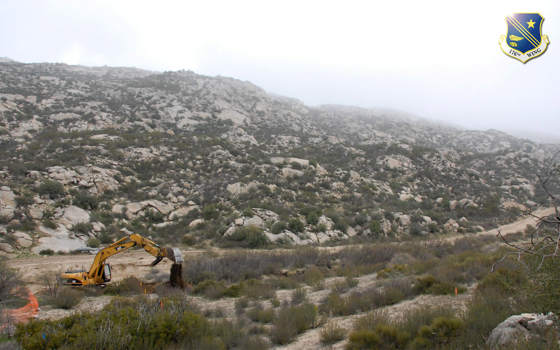 An excavator operated by a member of the 176th Wing's Civil Engineer Squadron improves a road used by the U.S. Border Patrol in the remote hills east of San Diego along the U.S.-Mexican border. Members of the 176 CES deployed to California for two weeks in 2008 as part of Operation Jump Start, a federal effort to help secure the border. Alaska Air National Guard photo by 2Lt John Callahan.