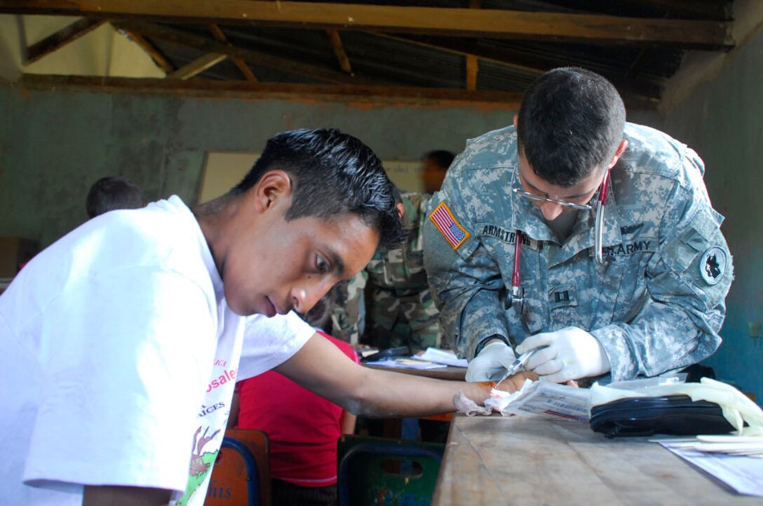 EL HORNO, Honduras - Army Capt. David Armstrong, Joint Task Force Bravo Medical Element flight surgeon, numbs a patients hand before removing a splinter that had been imbedded for more than a month Nov. 5. More than 650 patients were seen in the two day medical readiness exercise. (U.S. Air Force photo by Staff Sgt. Joel Mease)