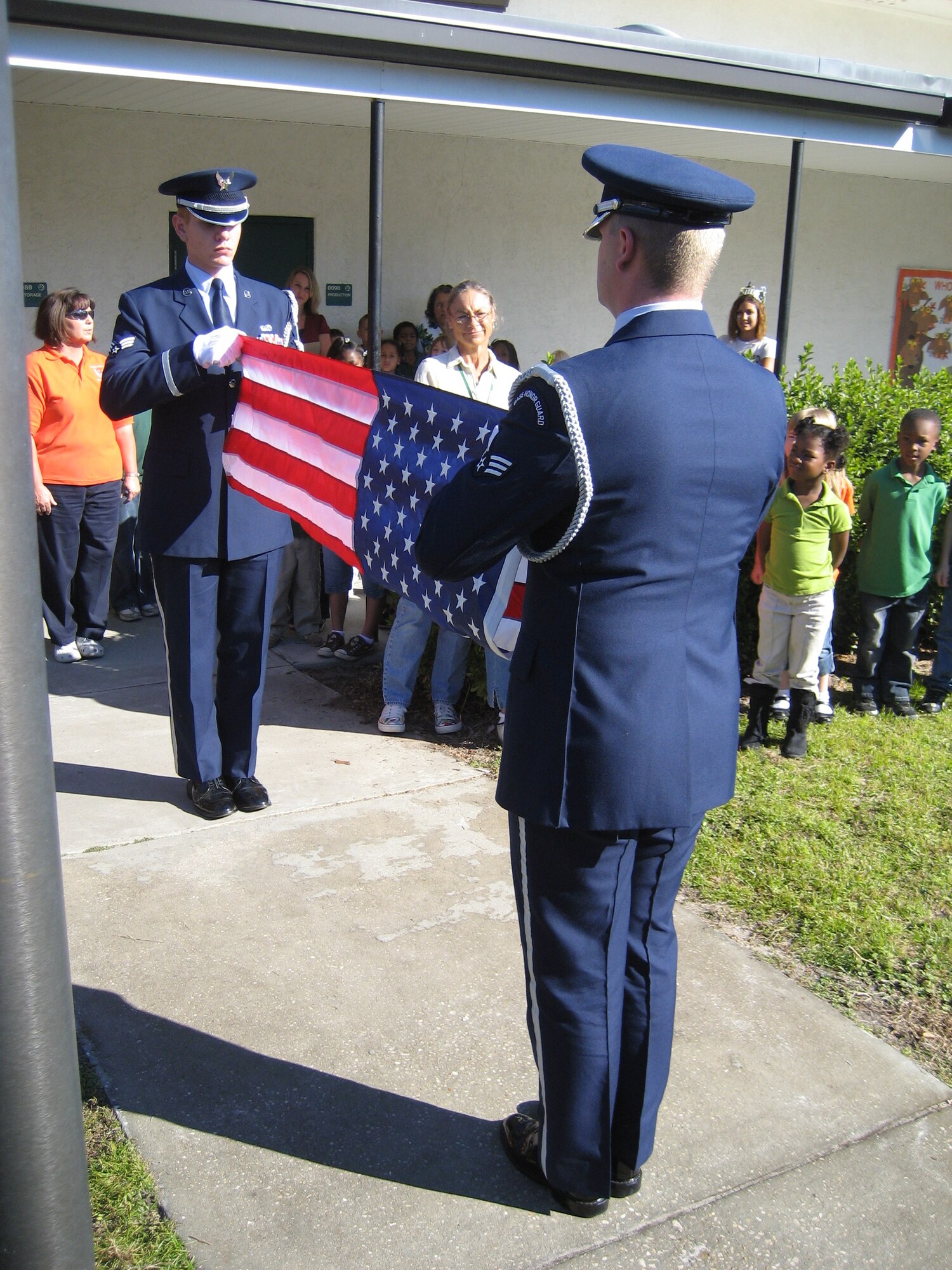 Two Tyndall Elite Honor Guard members, Senior Airmen Eric Graca (left) and Clinton Gibson (right), fold the American flag at Springfield Elementary today. The flag, which was donated to the school by the Ladies Auxiliary to the Veterans of Foreign Wars, was raised in front of students and teachers.