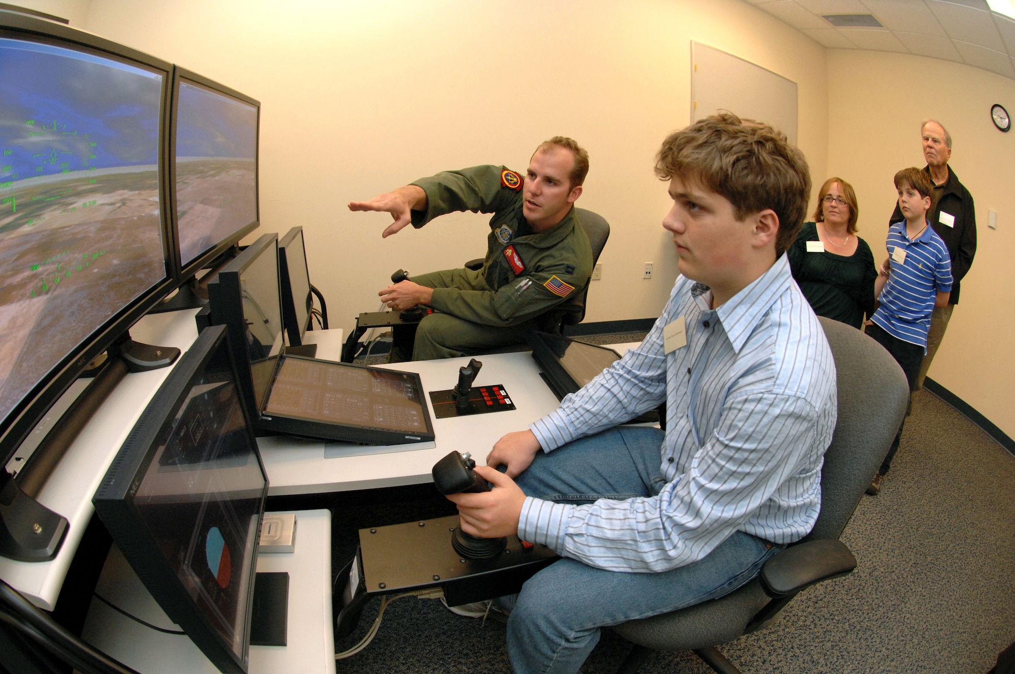 Capt. Brandon Shroyer, 21st Airlift Squadron C-1 pilot, gives Ray Neuberger, tips on flying the C-17 simulator while Robert Travis Jr., Debbie Travis-Neuberger and Roger Neuberger look on. The Travis family toured the C-17 training facility as part of guided tour of the base. The family traveled to Travis to witness the arrival of the final C-17 Globemaster III "The Spirit of Travis" Nov. 5. (U.S. Air Force photo/Nan Wylie)
