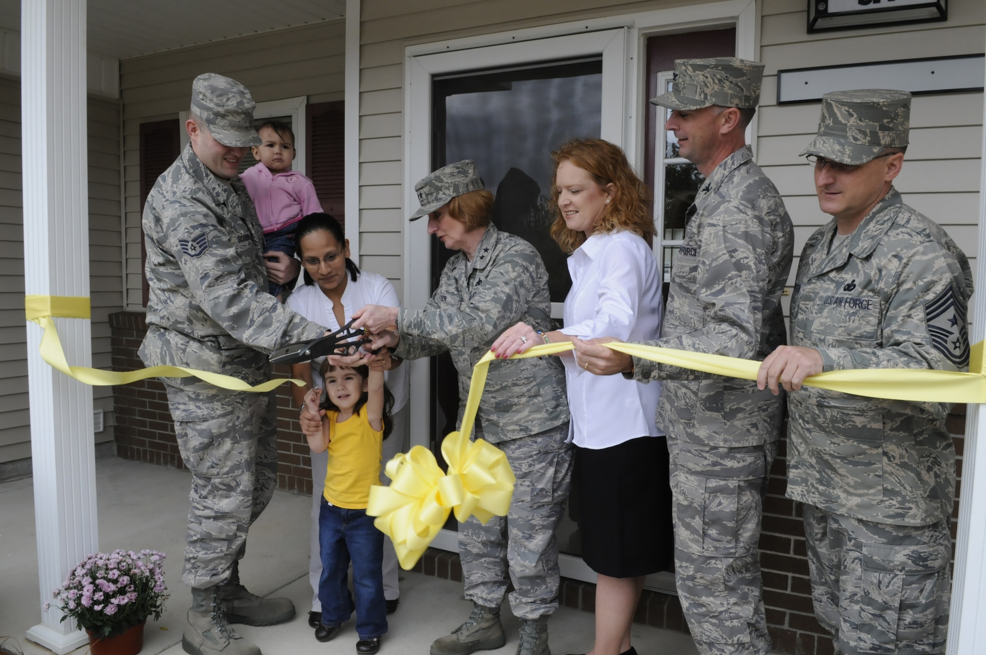 SSgt. Gabriel Scarberry with his wife Sabrina and children Ana, 3, and Ellis, 18 months, get assistance from Maj. Gen. Polly Peyer, Warner Robins Air Logistics Center commander, Lori Carver, Pinnacle Property Management, Col Warren Berry, 78th Air Base Wing commander and CMSgt. Harold Hutchison, 78th ABW command chief, to cut the ribbon on the Scarberry's newly renovated home in Turner Park managed by  Pinnacle Property Management. U. S. Air Force photo by Sue Sapp