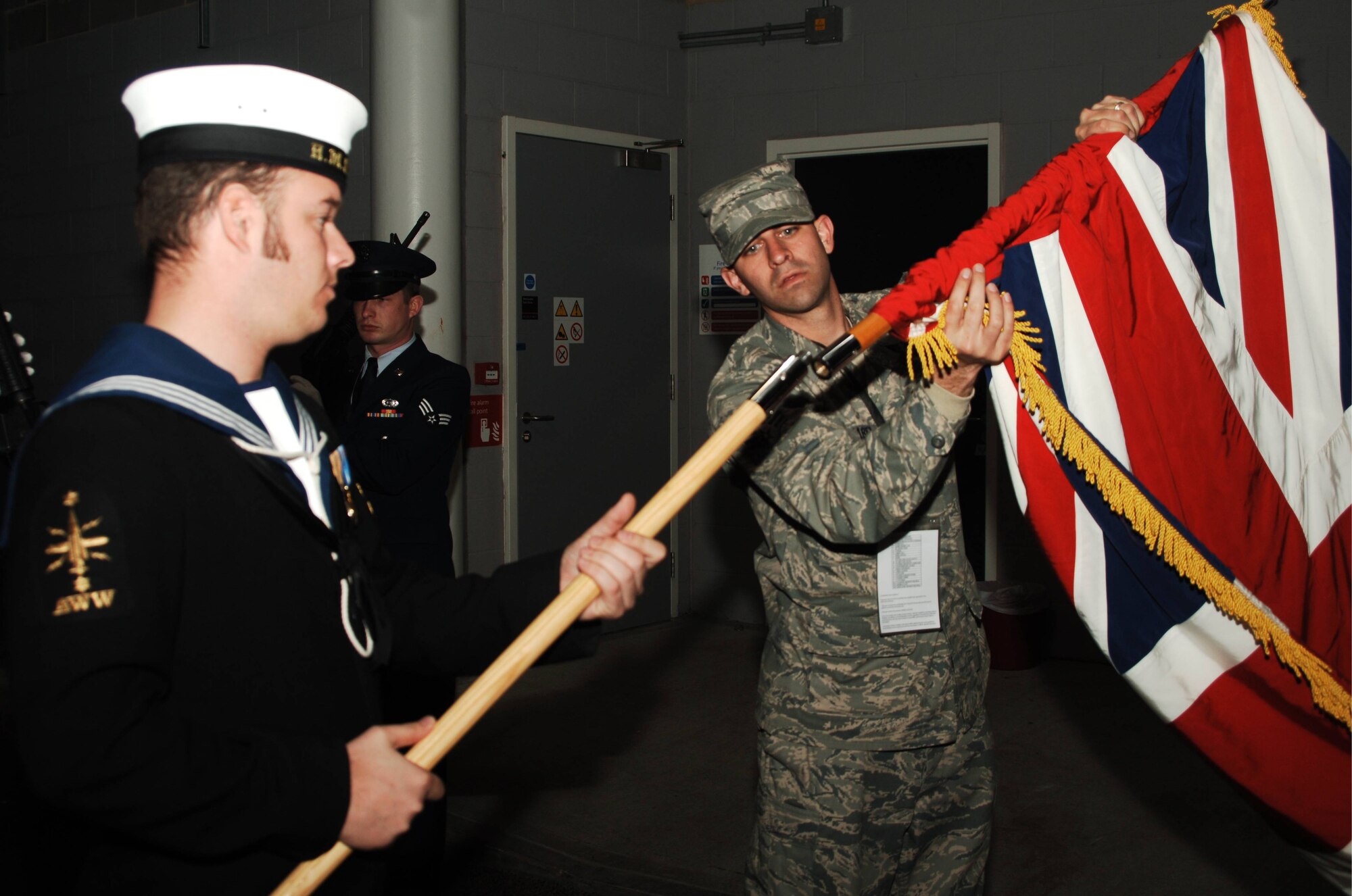 U.S. Air Force Senior Airman Manuel Minjarez of the JIOCEUR Honor Guard helps Royal Navy Leading Seaman Tim Mills  to assemble the flag of the United Kingdom before the opening ceremonies of the October 26, 2008 NFL game played in London, England.  (U.S. Air Force photo by Staff Sgt. Chad E. Chisholm)