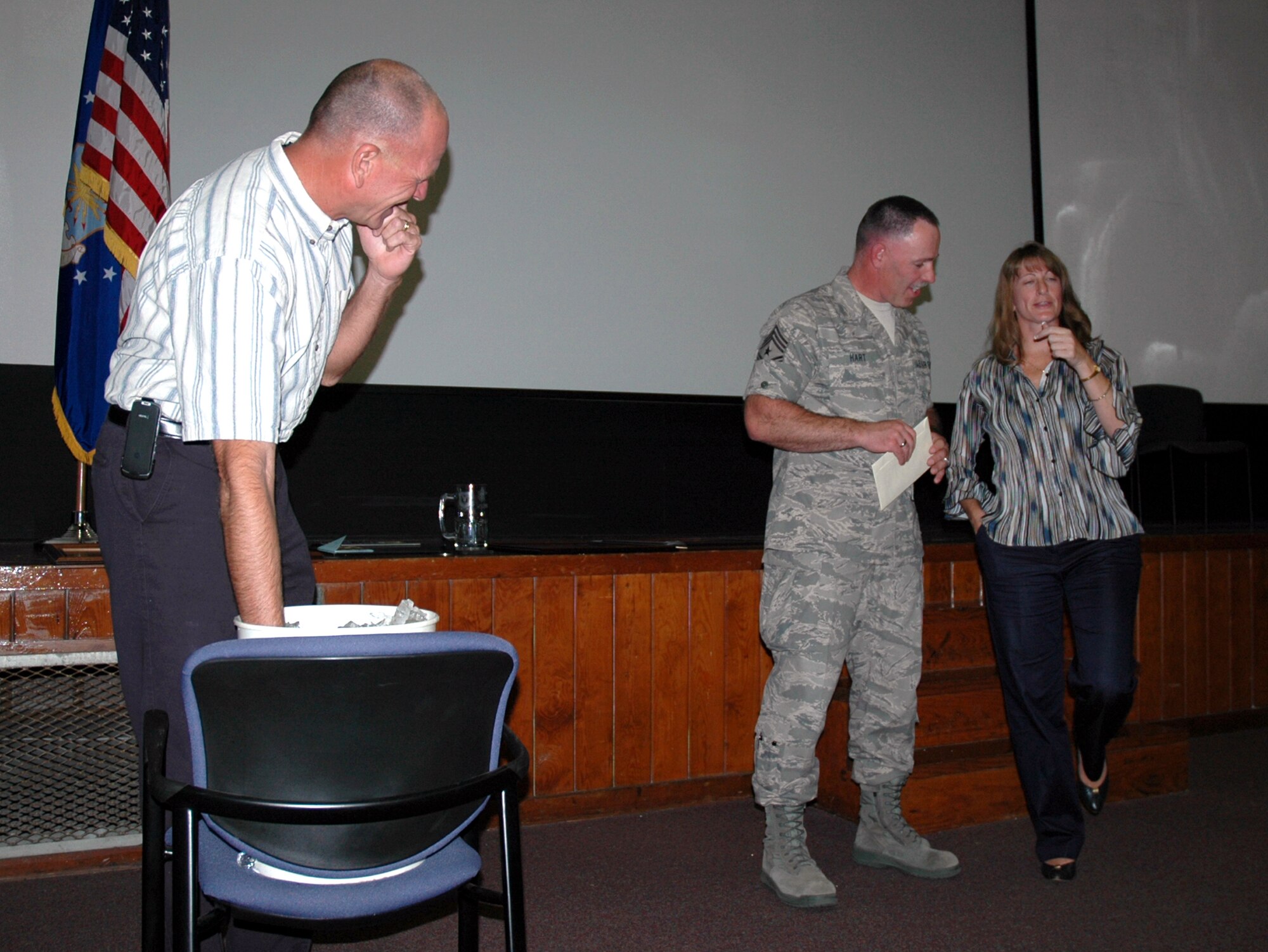 Chief Master Sgt. Rocky Hart, outgoing 919th Special Operations Wing command chief (center) shows his humorous method of preventing long-winded speeches at his sendoff party Sunday at Duke Field. Left, Lynn Dominique, 919th SOW honorary commander keeps his hand submerged in a bucket of ice, while Shelley Normand, 919th Operations Group honorary commander, teeters on one leg as both delivered accelerated farewells. Chief Hart was honored on his final duty day during the unit training assembly. The chief now moves on to assume the command chief role for the 310th Space Wing (Reserve) at Schriever Air Force Base, Colo. (U.S. Air Force Photo\Senior Airman Jon McCallum)