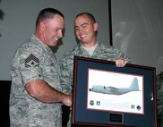 Chief Master Sgt. Rocky Hart, outgoing 919th Special Operations Wing command chief, receives a unit memento from Airman James Knudsen, the 919th Maintenance Squadron's newest Airman, during a going away ceremony held Sunday at Duke Field. Chief Hart now moves on to assume the command chief role for the 310th Space Wing (Reserve) at Schriever Air Force Base, Colo. (U.S. Air Force Photo\Senior Airman Jon McCallum)