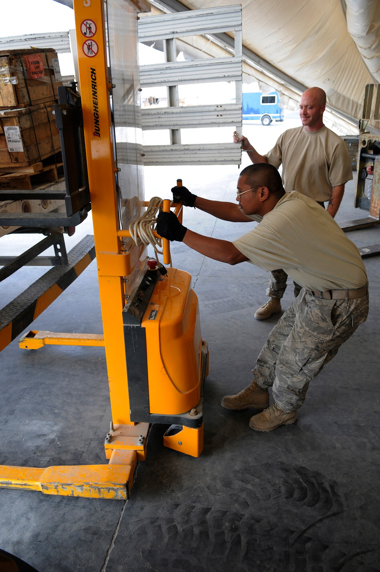 Staff Sgt. Daryl Reid, 379th Expeditionary Logistics Readiness Squadron, holds the tailgate open as Senior Airman Moises Maramba, 379 ELRS, loads a box onto a truck using a half-ton electric stacker, Nov. 6, at an undisclosed air base in Southwest Asia.  The box contains a pump assembly for a C-130 Hercules and is being transported to the 379th Expeditionary Aircraft Maintenance Squadron hydraulic maintenance shop, as a replacement part.  Sergeant Reid, a native of Phoenix, Ariz., is deployed from Mountain Home Air Force Base, Idaho.  Airman Maramba hails from the Bronx, N.Y., and is deployed from MacDill AFB, Fla.  Both are deployed in support of Operations Iraqi and Enduring Freedom and Joint Task Force-Horn of Africa.  (U.S. Air Force photo by Tech. Sgt. Michael Boquette/Released)