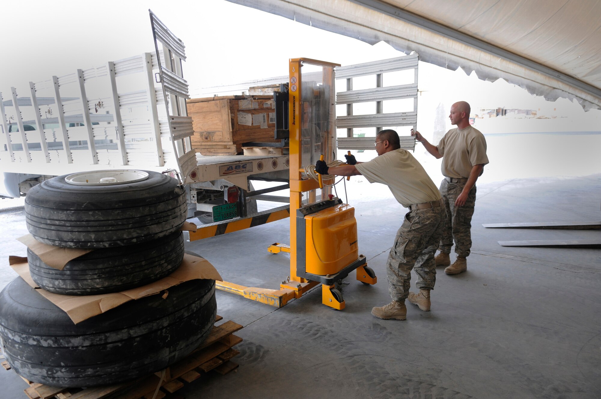 Staff Sgt. Daryl Reid, 379th Expeditionary Logistics Readiness Squadron, holds the tailgate open as Senior Airman Moises Maramba, 379 ELRS, loads a box onto a truck using a half-ton electric stacker, Nov. 6, at an undisclosed air base in Southwest Asia.  The box contains a pump assembly for a C-130 Hercules and is being transported to the 379th Expeditionary Aircraft Maintenance Squadron hydraulic maintenance shop, as a replacement part.  Sergeant Reid, a native of Phoenix, Ariz., is deployed from Mountain Home Air Force Base, Idaho.  Airman Maramba hails from the Bronx, N.Y., and is deployed from MacDill AFB, Fla.  Both are deployed in support of Operations Iraqi and Enduring Freedom and Joint Task Force-Horn of Africa.  (U.S. Air Force photo by Tech. Sgt. Michael Boquette/Released)