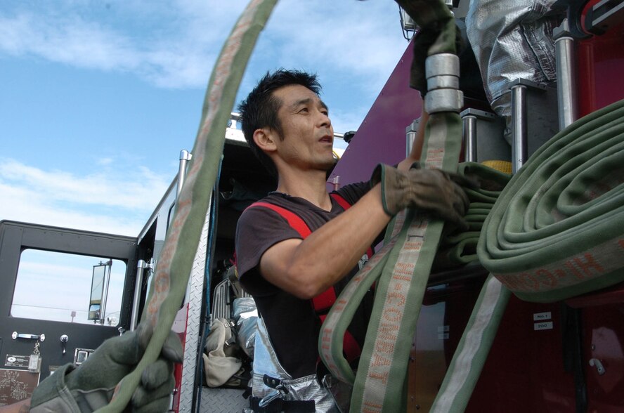 Kazuaki Nishide from the 374th Civil Engineer Squadron, pulls a hose onto a truck during a simulated fire Oct. 29. Japanese National firefighters work along side the Airmen of Yokota Air Base in work and exercises everyday. (U.S. Air Force photo by Airman Sean Martin)