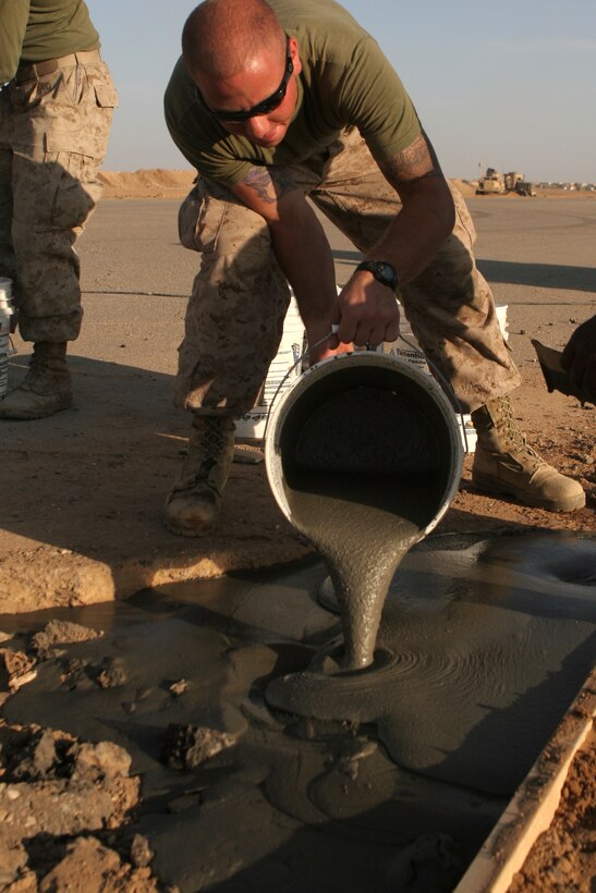 Cpl. Justin S. Sher, a 21 year old combat engineer, Marine Wing Support Squadron 273, pours concrete into a crater caused by erosion on the Camp Sinjar airstrip.  These Marines are repairing the airstrip to make it capable of supporting F/A-18's.  This is also the only Marine run airstrip in the Nineweh province, in support of the Marine Air Ground Task Force participating in Operation Defeat Al-Qaida in the North II.