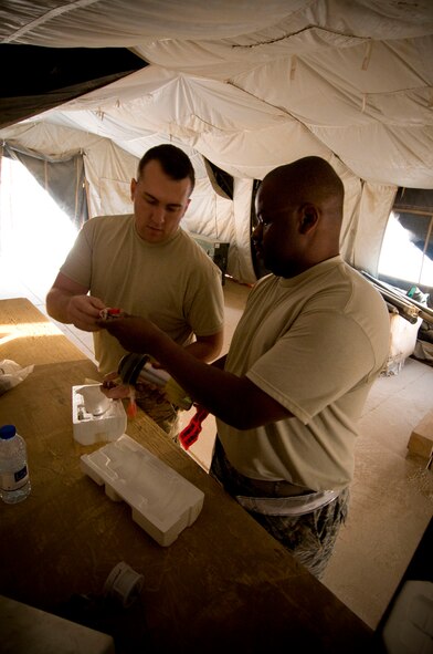 Staff Sgt. Jared Wood and Master Sgt. James Bradley, 451st Air Expeditionary Group Logistics Flight-Ammo, inspect FMU-143 joint programmable fuzes at Kandahar Air Field, Afghanistan, Oct. 27, 2008. Part of the ammo role is to perform operation and function checks to ensure that the bombs and missiles will detonate when they are supposed to. The three-man team at Kandahar Air field achieved an impressive 100 percent success rate with their munitions. Sergeant Wood is deployed from Langley Air Force Base, Va., and Sergeant Bradley is deployed from Minot Air Force Base, N.D. (U.S. Air Force photo by Staff Sgt. Samuel Morse/Released)