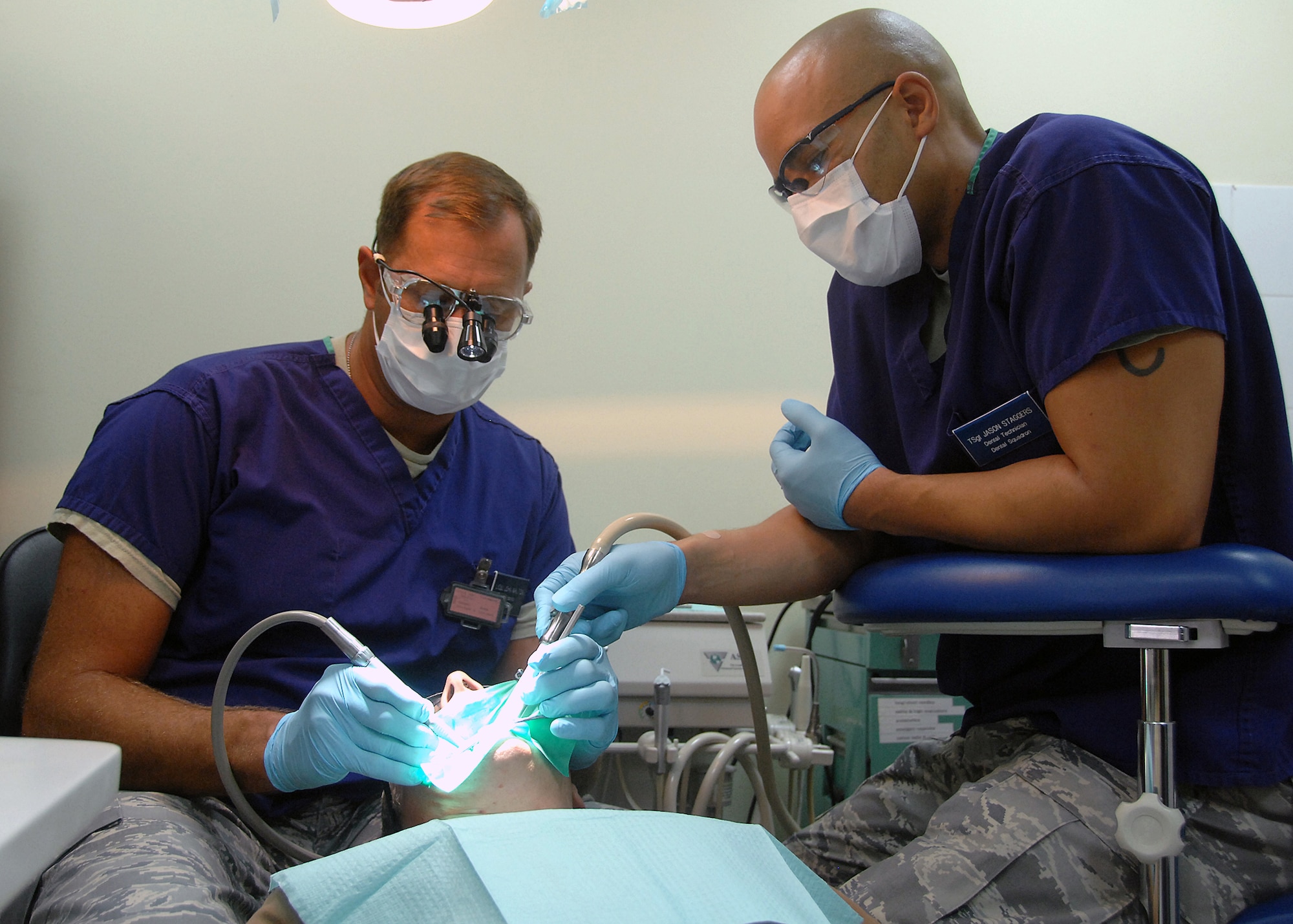 SOUTHWEST ASIA -- Lt. Col John Walton and Tech. Sgt. Jason Staggers, 386th Expeditionary Medical Group dental clinic, work together to repair Australian Air Force Sergeant Courtenay Brockman's broken tooth during an emergency visit on Nov. 4 at an air base in Southwest Asia. The dental clinic provides urgent care treatment to 386th Air Expeditionary Wing members, sister services and coalition members. Colonel Walton and Sergeant Staggers are deployed from Wright-Patterson Air Force Base, Ohio. (U.S. Air Force photo/Tech. Sgt. Raheem Moore)