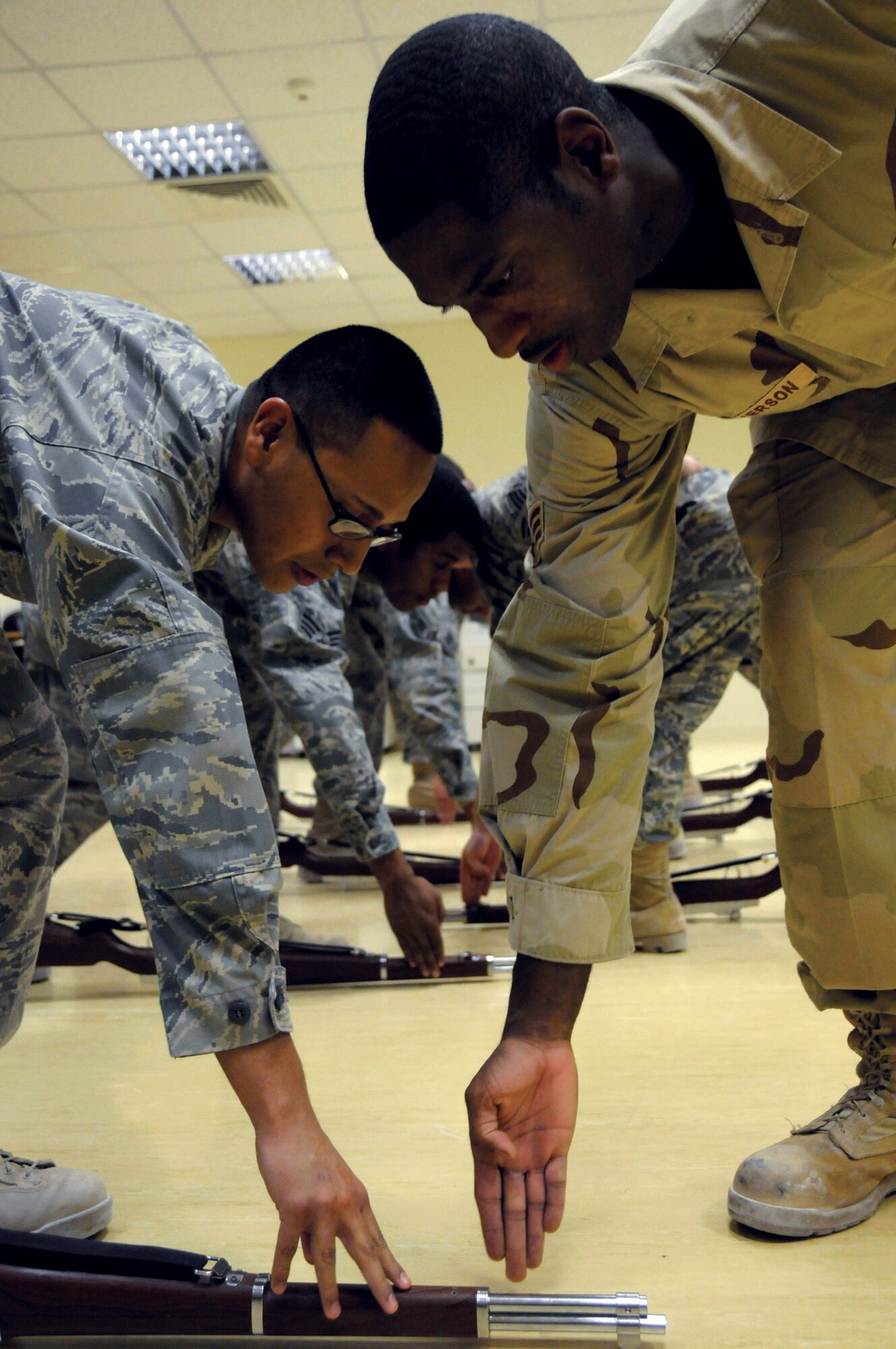 Senior Airman Eric Perez, 379 ECES, (left) receives instructions from Senior Airman Dereck Hutcherson, 379 ECES, on performing the command of ground arms during honor guard practice Oct. 28, at an undisclosed location in Southwest Asia. Airman Perez, a native of Houston, Texas, is deployed from Misawa Air Base, Japan, and Airman Hutcherson, a native of Atlanta, Ga., is deployed from Grand Forks AFB, N.D. (U.S. Air Force photo by Staff Sgt. Darnell T. Cannady)