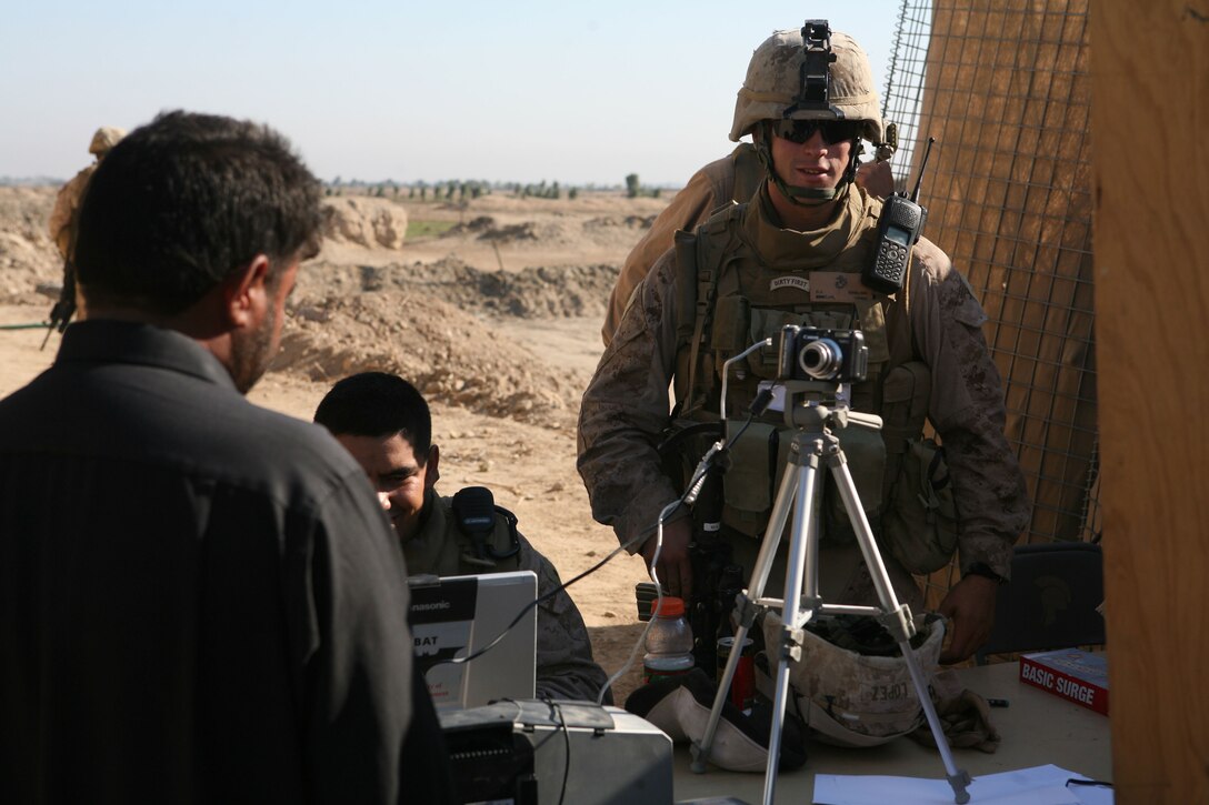 Marines with Company C, 1st Battalion, 4th Marine Regiment, Regimental Combat Team 1, take photos of civilians during a remote badge operation at the Abuyuset area near Fallujah, Iraq, Nov. 8. Personal photos and information are included on the badges, which are required to pass through Iraq’s entry control points.