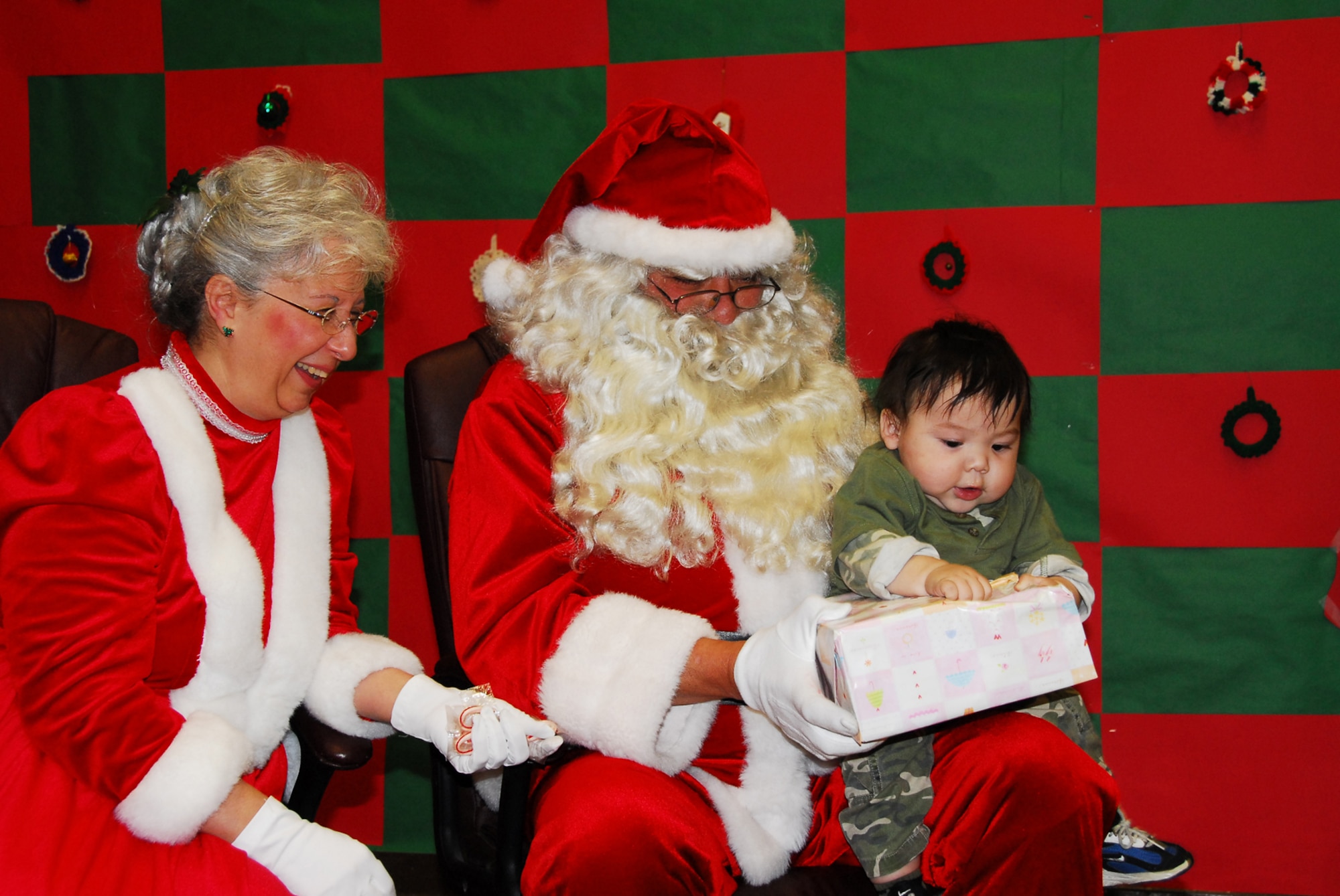 RUBY, Alaska -- Santa and Mrs. Claus deliver the first present to Levi Williams during the Alaska National Guard's Operation Santa Claus Nov. 5. Ruby was the first village Operation Santa Claus, which is celebrating its 52nd anniversary, visited this year. This event is part of the Alaska National Guard's yearly community relations and support program that provides clothing, books, school supplies and toys for youngsters in communities across the state each year during the holidays. (U.S. Army photo/Kalei Brooks)