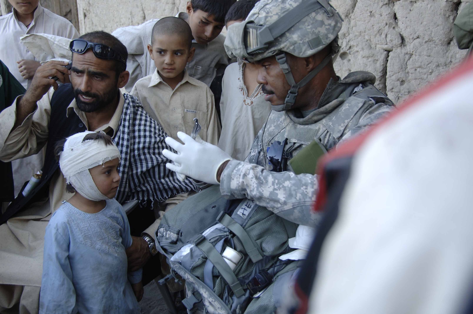 Air Force Tech. Sgt. William Allison, 436th Medical Operation Squadron, Dover Air Force Base, Delaware, provides medical aid to an Afghan child during a foot patrol Nov. 8 in Nangarhar Province.  He is part of the Nangarhar Provincial Reconstruction Team.  The PRT is made up of Airmen and Soldiers from around the world and is charged with assisting the provincial government in improving security, governance and reconstruction.  His hometown is Detroit, Michigan.  (Courtesy photo/Released)