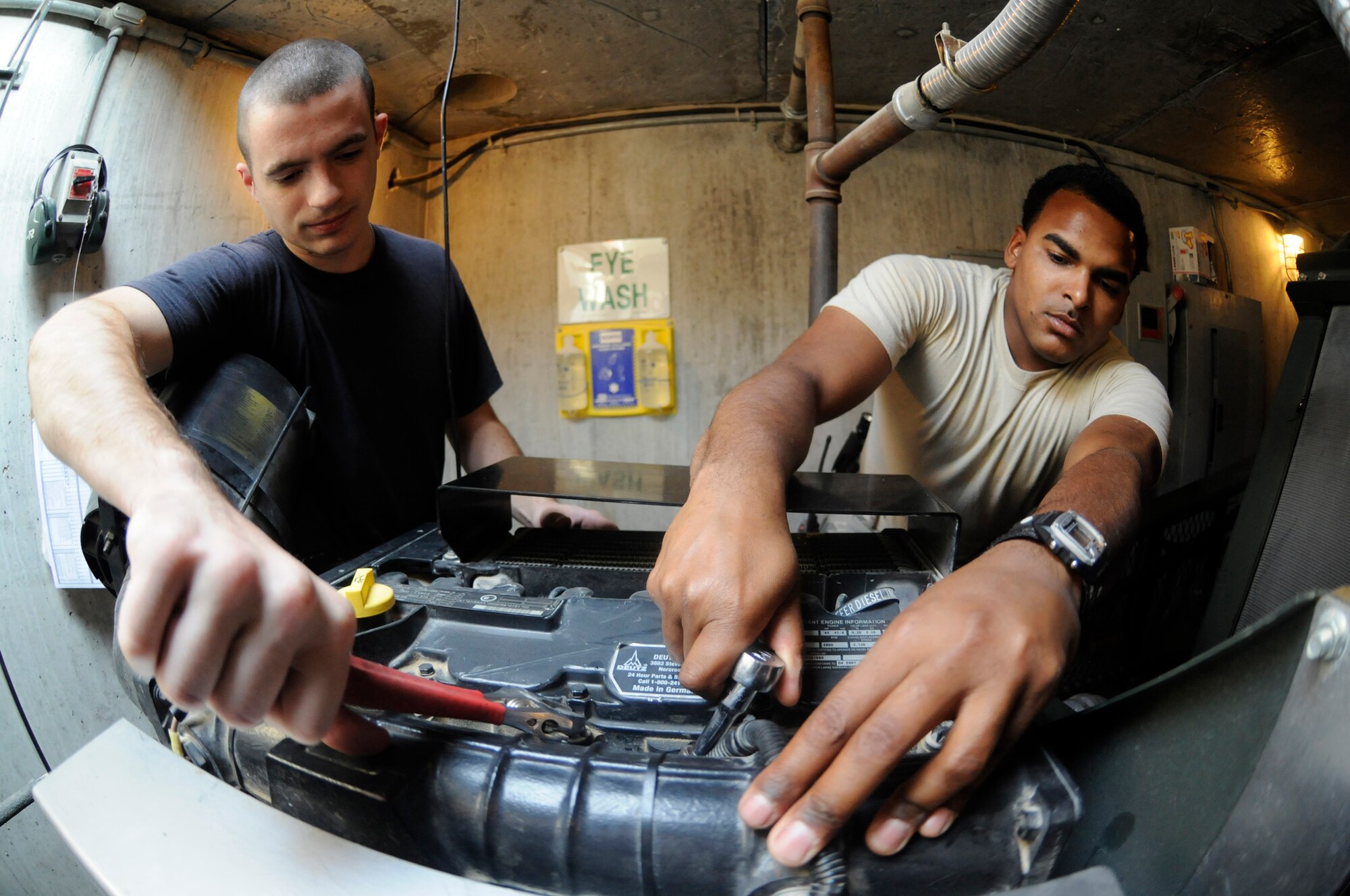 Senior Airman Daniel Wright and Senior Airman Osealoa McNabb, both barrier maintenance journeymen assigned to the 379th Expeditionary Civil Engineer Squadron, bleed the hydraulic system of an aircraft arresting system as part of a weekly inspection conducted Nov. 7, at an undisclosed air base in Southwest Asia.  These barrier maintenance members are responsible for ensuring the AAS is operational and ready to save pilot and aircraft in the event of a brake failure emergency landing. Airman Wright, a native of Cookeville, Tenn., is deployed from Ramstein Air Base, Germany.  Airman McNabb, a native of Newark, N.J., is deployed from McChord Air Force Base, Wash.  Both are deployed in support of Operations Iraqi and Enduring Freedom and Joint Task Force-Horn of Africa. (U.S. Air Force photo by Staff Sgt. Darnell T. Cannady/Released)