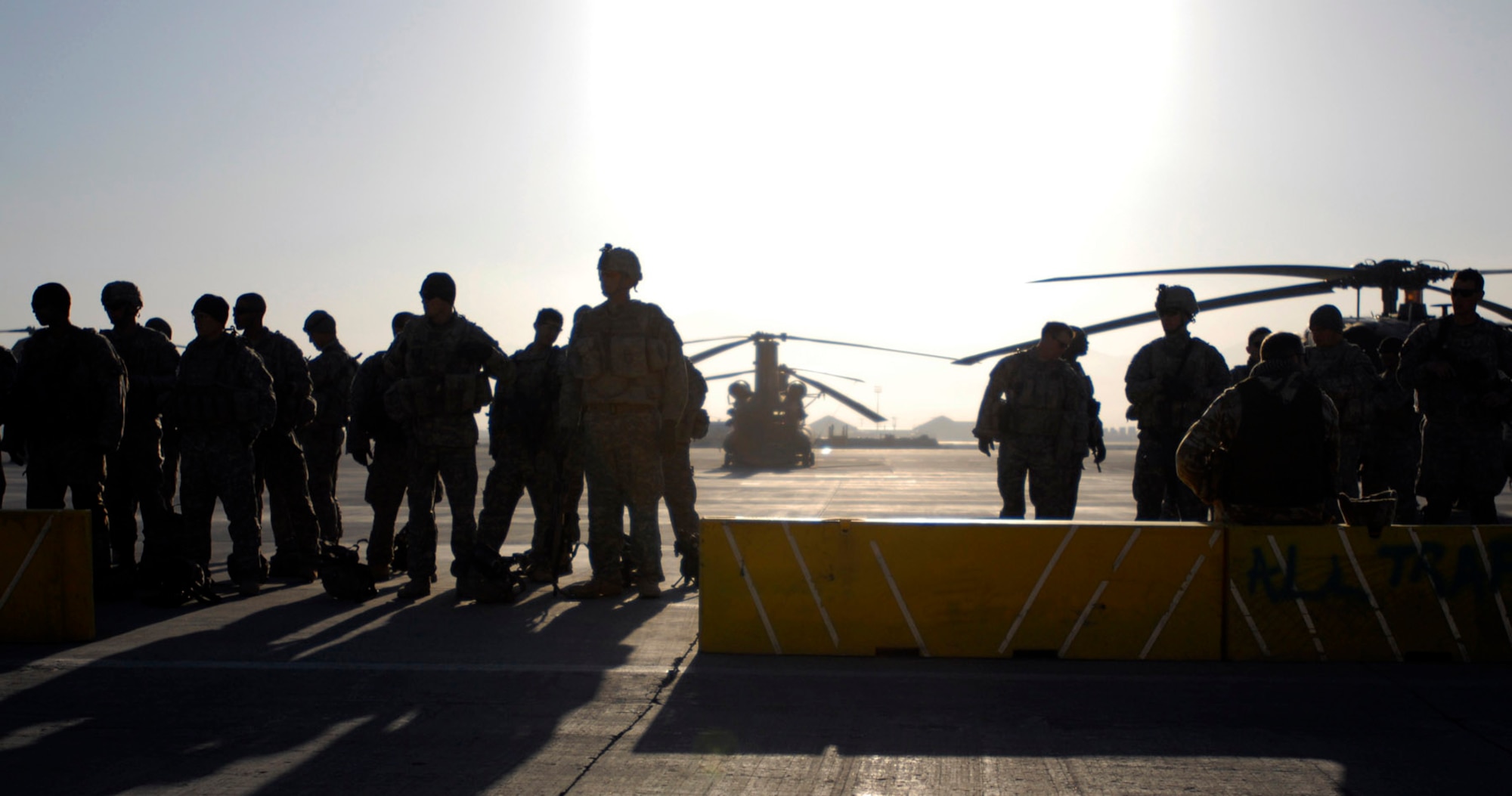 Silhouetted by the morning sun, Soldiers with the 101st Division Special Troops Battalion, 101st Airborne Division wait on the flightline at Bagram Air Field, Afghanistan, Nov. 4.  The Soldiers went on an air assault mission to a narrow valley in eastern Afghanistan and searched for IED making materials. (Photo by Spc. Mary L. Gonzalez, CJTF-101 Public Affairs)