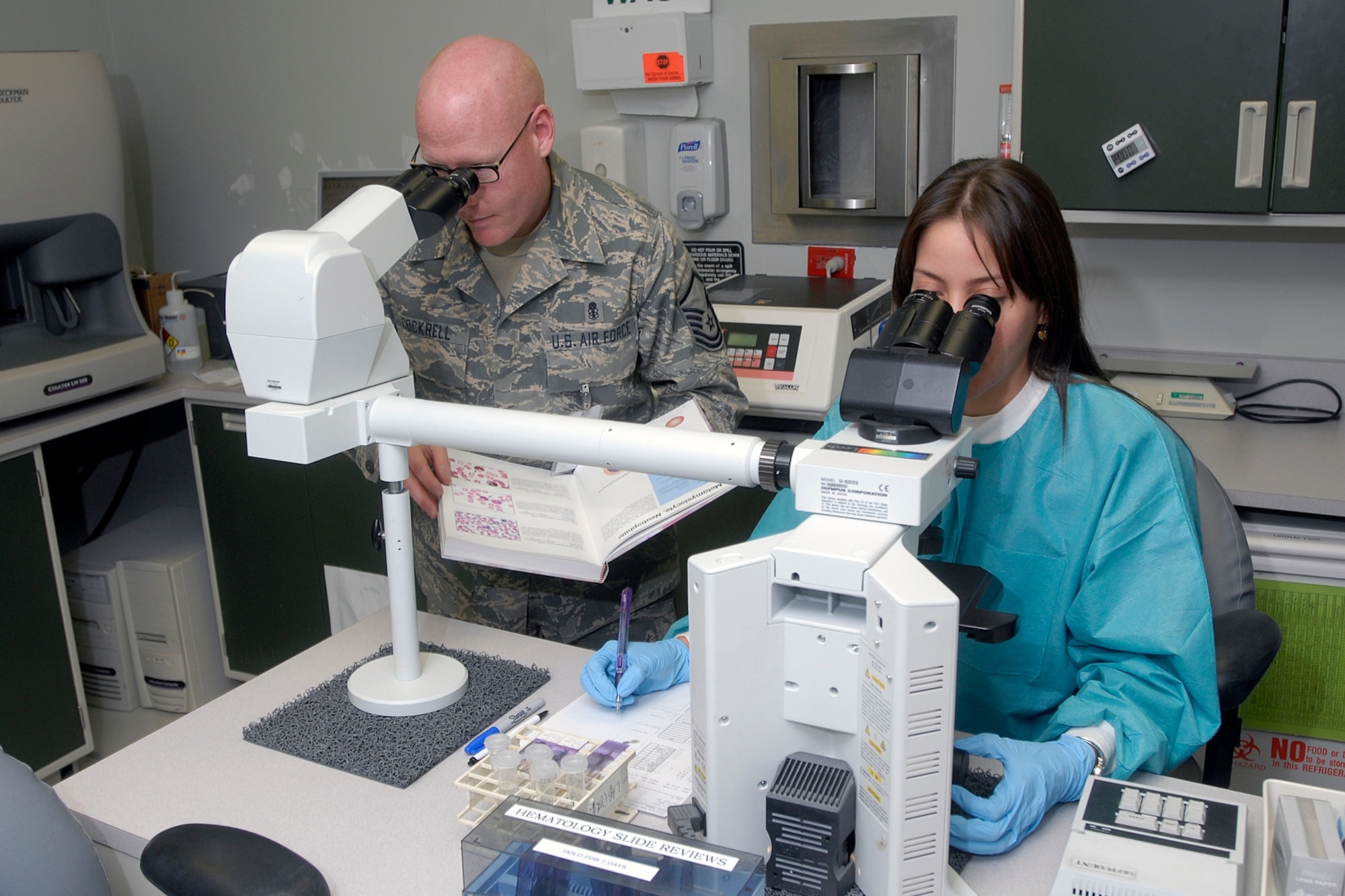 21st Medical Group Laboratory personnel made a potential life-saving medical catch during a routine blood test Sept. 29. Alexander Andujar (right) performs a microscopic inspection of a blood sample  Master Sgt. Dan Cockrell (left), in the 21st MDG's Clinical Laboratory. It was a test similar to the one seen here that may have saved a 12-year-old boy's life. (U.S. Air Force photo/Larry Hulst)