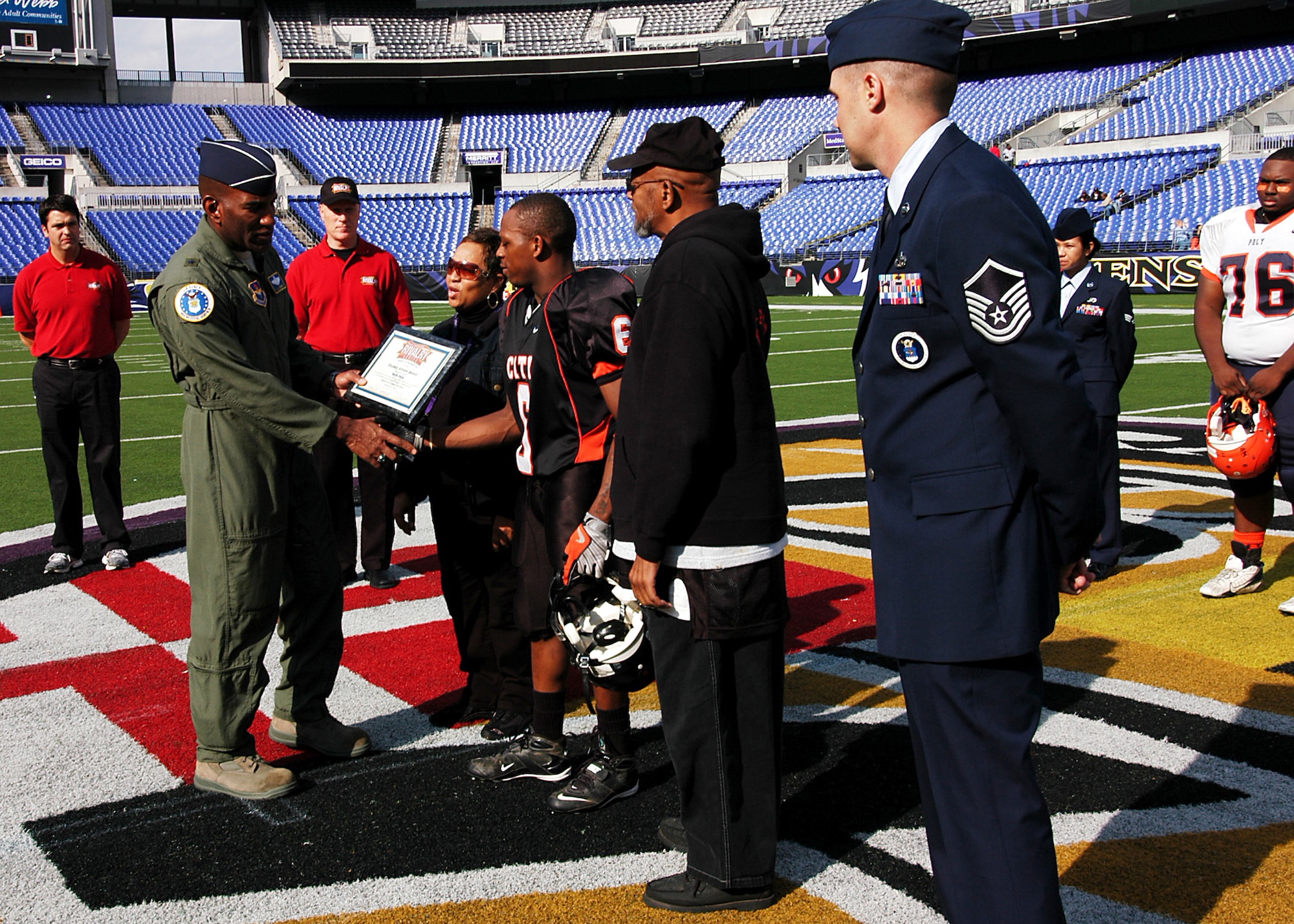 Air Force Recruiting Service Commander Brig. Gen. A.J. Stewart presents Knights player Malik Pack of Baltimore City College high school’s football team a $500 college scholarship before game time at M&T Bank Stadium Nov. 8. The Knights were set to play its 119-year rival, the Baltimore Polytechnic Institute Engineers in the Air Force-sponsored iHigh Great American Rivalry Series. A Class of 1977 BPI alumni, General Stewart shared inspirational words with both teams before the game and presented two $500 college scholarships to City College and BPI players. Master Sgt. Christopher Claar, far right, 317th RCS Baltimore City-area recruiter, supports the presentation. (U.S. Air Force photo/Tech. Sgt. Jennifer Lindsey)