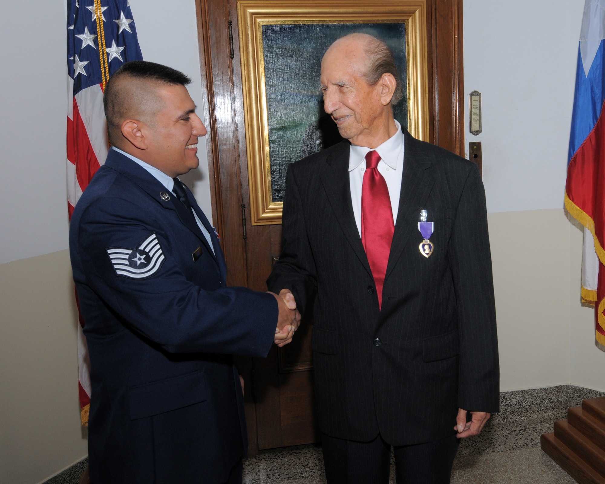 Hilario Riojas (right) shakes hands with Tech. Sgt. Gilbert Perez, Mr. Riojas' granddaughter's husband and a Reservist from Lackland Air Force Base, during a Purple Heart ceremony Monday. Col. Jacqueline Van Ovost, 12th Flying Training Wing commander, presented the Purple Heart to the World War II veteran and former Army Air Forces corporal, who was wounded by artillery shell shrapnel during a battle in Germany more than 60 years ago. (U.S. Air Force photo by Melissa Peterson)