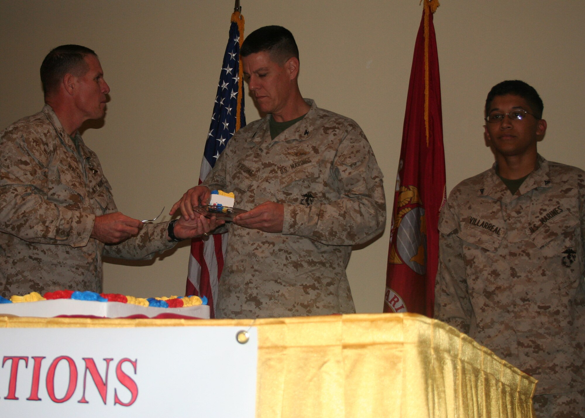 Brig. Gen. Robert Walsh, 2nd Marine Aircraft Wing assistant commander, hands a piece of cake to Col. Patrick O’Rourke, 2nd MAW. Also on stage is Lance Cpl. Lorenzo Villareal, 2nd MAW. Colonel O’Rourke and Corporal Villareal were the oldest and youngest Marines present during the ceremony here at Lajes Field commemorating the 233rd birthday of the Marine Corps. (U.S. Air Force photo by 1st Lt. George Tobias)