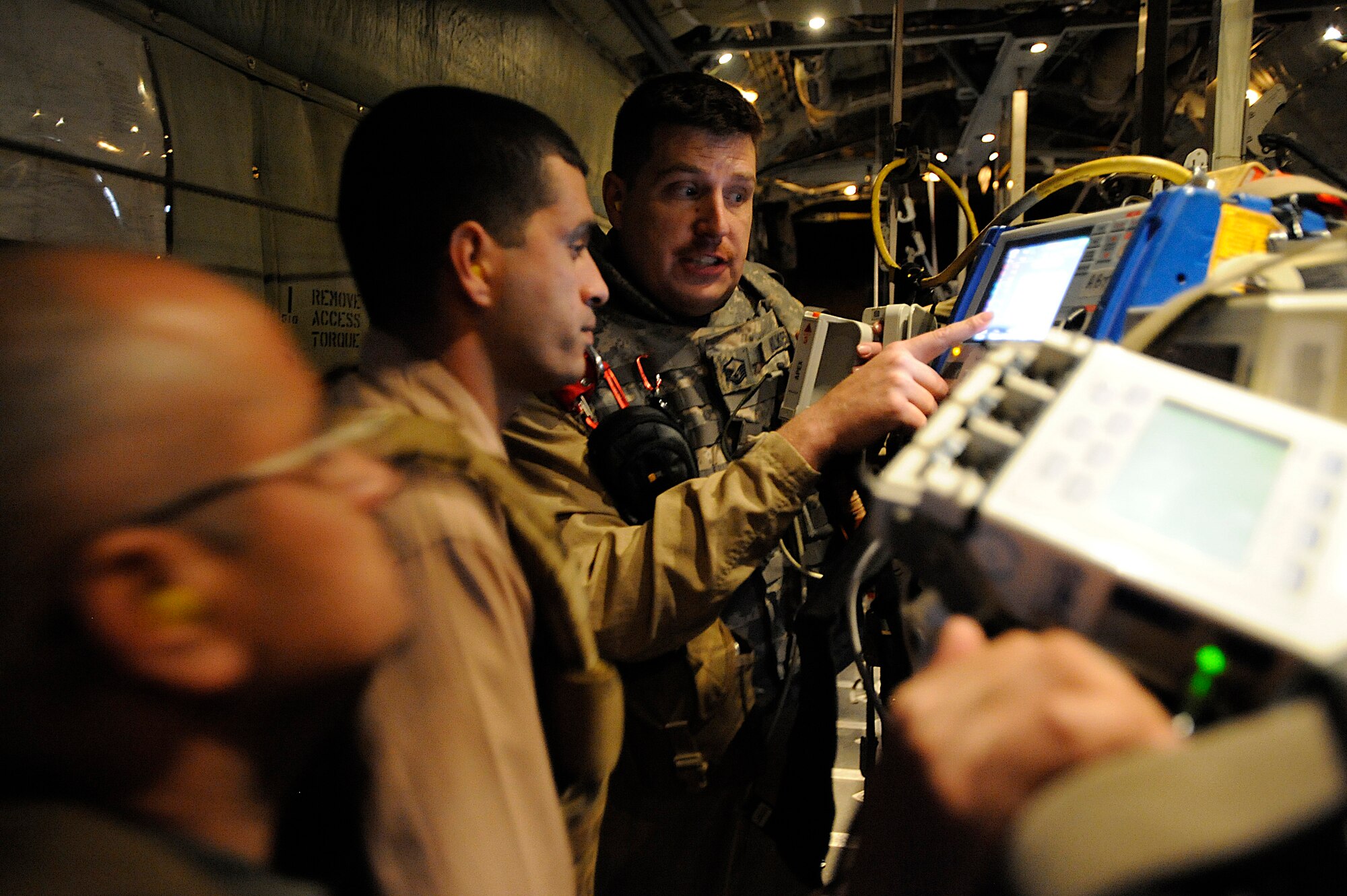 Master Sgt. Scott Wilkes (right) demonstrates a defibrillator and heart monitor to Iraqi air force Capt. (Dr.) Mohammed (middle) and Iraqi air force Maj. (Dr.) Abdul-Razaq during an aeromedical evacuation mission over Iraq Nov. 7. The two Iraqi doctors from Iraq's Ministry of Defense accompanied the U.S. Air Force mission to study aeromedical evacuation procedures so that they can establish an aeromedical evacuation service for the Iraqi air force. Wilkes, a charge medical technician with the 332nd Expeditionary Aeromedical Evacuation Flight, is deployed from McGuire Air Force Base, N.J. (U.S. Air Force photo/Airman 1st Class Jason Epley)