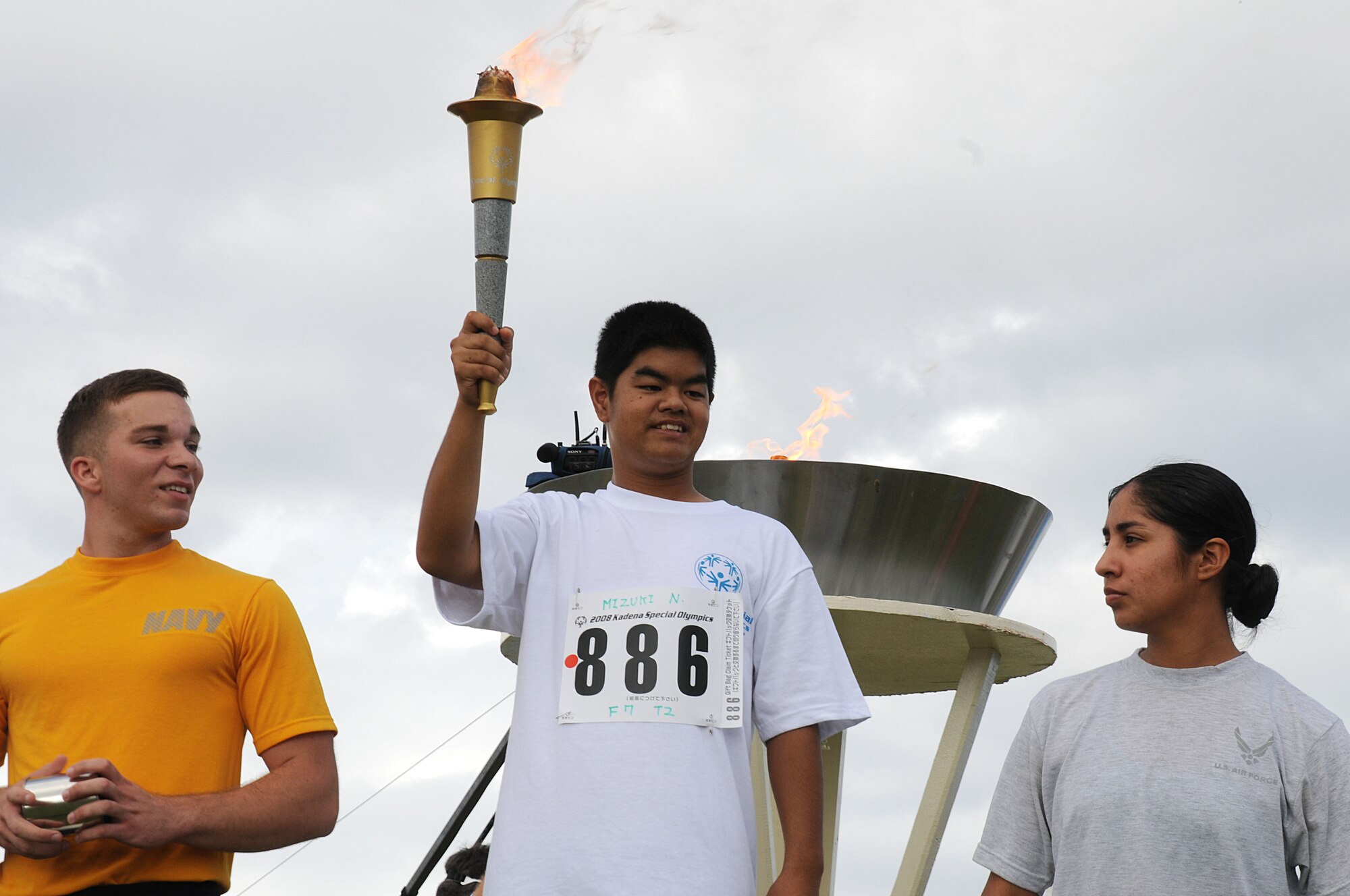 Members of the Navy and Air Force stand with Mizuki-san as he holds up the Olympic torch after lighting the cauldron signaling the start of the Special Olympics Games Nov. 8, 2008, at Kadena Air Base, Japan. Kadena hosted the 9th Annual Special Olympic Games and Art Festival for special needs Okinawan and American athletes. (U.S. Air Force photo/Staff Sgt. Chrissy Best)   
                                             