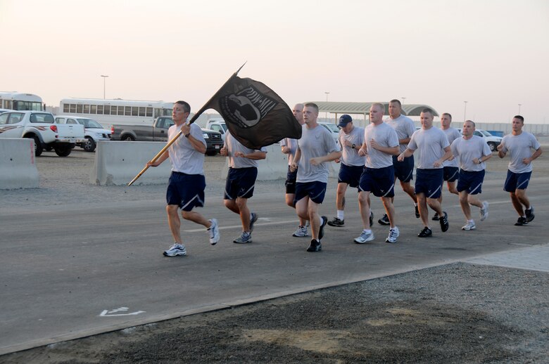 SOUTHWEST ASIA -- Members of the 380th Air Expeditionary Wing pay tribute to all veterans by running with a prisoner of war/missing in action flag here Nov. 11. The 380th is celebrating Veterans Day with a 24 hour Memorial Run carrying a POW/MIA flag around the compound with over 100 volunteer runners. (U.S. Air Force photo/Tech. Sgt. Christopher A. Campbell)(released)