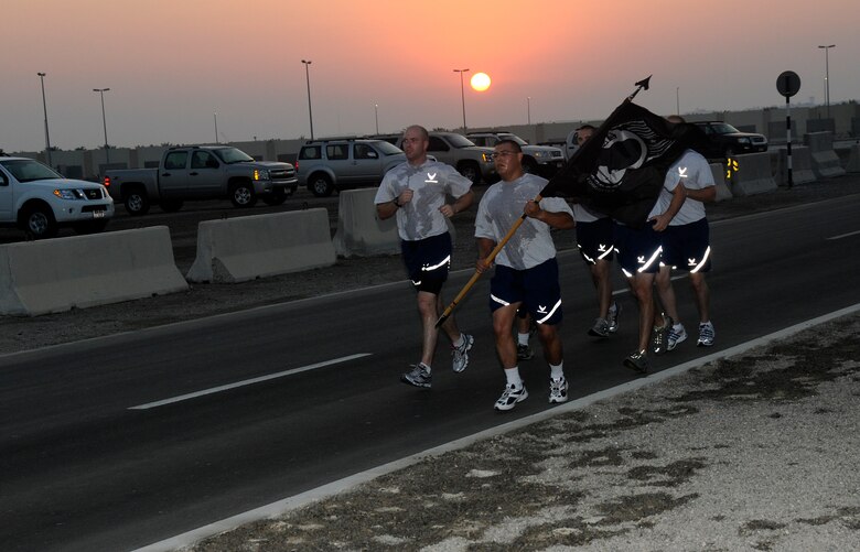 SOUTHWEST ASIA -- Members of the 380th Air Expeditionary Wing pay tribute to all veterans by running with a prisoner of war/missing in action flag here Nov. 11. The 380th is celebrating Veterans Day with a 24 hour Memorial Run carrying a POW/MIA flag around the compound with over 100 volunteer runners. (U.S. Air Force photo/Tech. Sgt. Christopher A. Campbell)(released)
