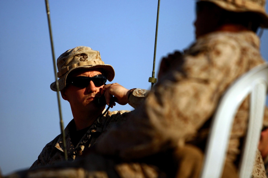 Capt. Dave "Penguin" Merrit, a 30-year-old air officer with Headquarters and Support Company, 3rd Battalion, 7th Marine Regiment, Regimental Combat Team 5, from Wilbraham, Mass., sends his commands to two helicopters as they as they shoot a storage container during an exercise at Combat Outpost Rawah, Iraq, Dec. 12.  The exercise allowed the pilots and the Marines on the ground to maintain their skills while deployed.::r::::n::