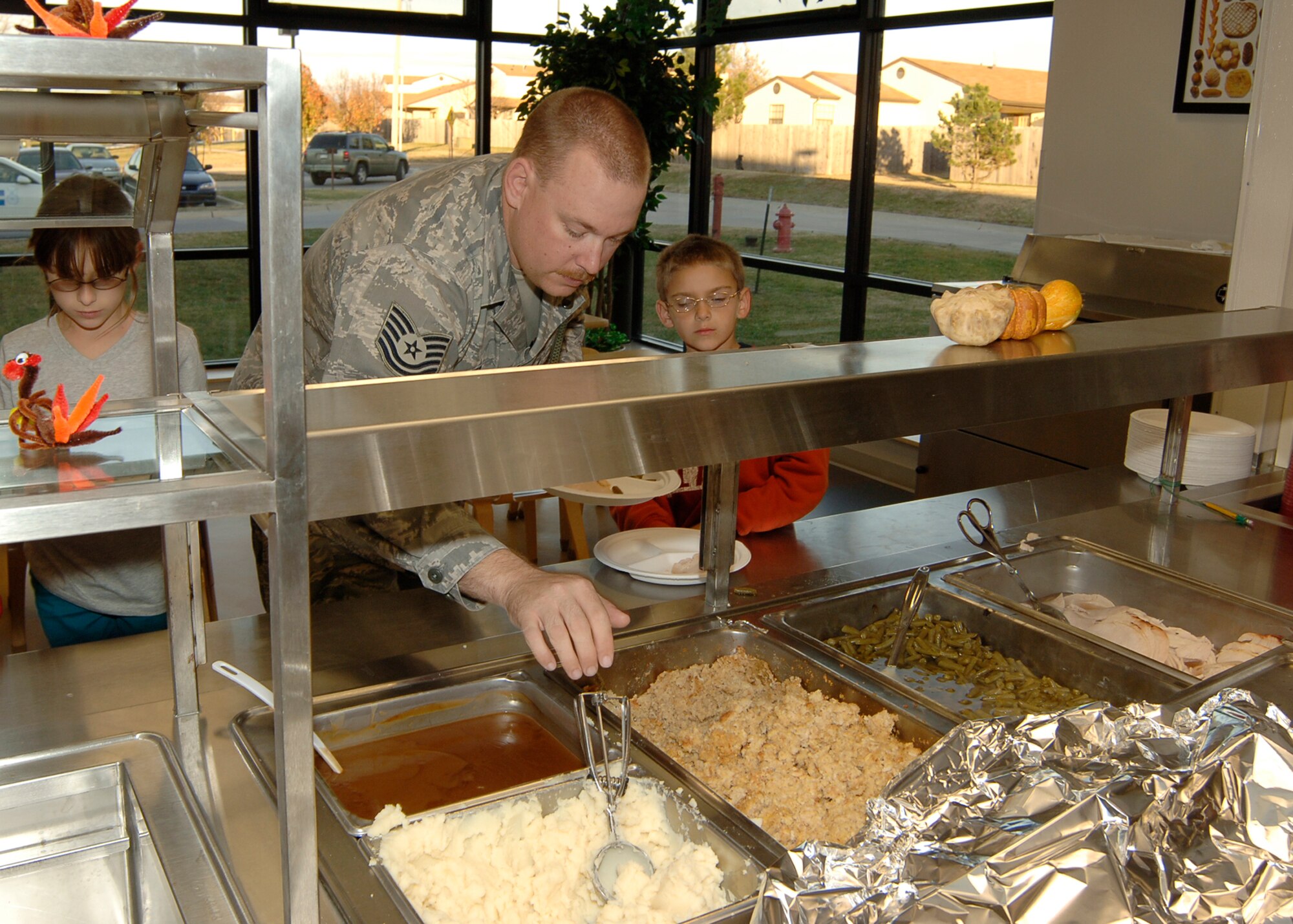 MCCONNELL AIR FORCE BASE, Kan. -- Tech. Sgt. Jarod Shaffer, 22nd Security Forces Squadron, serves a helping of mashed potatoes to his son and daughter, Nathan and Samantha, at the School Age Program building during the Harvest Feast, Nov. 7. During the event, they showed a slideshow of the SAP students from the different year round events was shown. (Photo by Airman 1st Class Maria Ruiz)