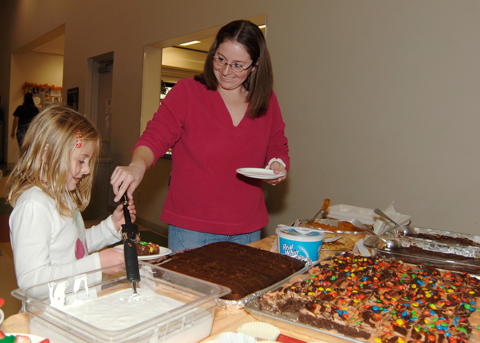 MCCONNELL AIR FORCE BASE, Kan. -- Erinn Jones, wife of Tech. Sgt. Brad Jones, 22nd Operations Support Squadron, serves a helping of brownies to her daughter Brynn at the School Age Program building during the Harvest Feast, Nov. 7. The different SAP groups offered turkey, green beans, stuffing, cranberry sauce and many different desserts. (Photo by Airman 1st Class Maria Ruiz)