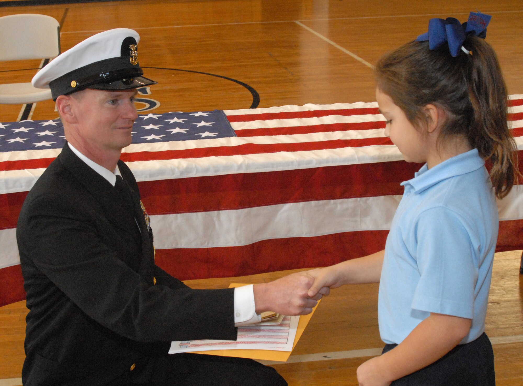 Master Chief Petty Officer Paul Zimmerman, Navy Senior Enlisted Leader, Center for Information Dominance Detachment, Goodfellow Air Force Base, Texas, accepts a gift of cards and drawings from the students of Angelo Catholic School, San Angelo, Texas at a Veterans' Day Ceremony on Nov. 11. Sailors from Goodfellow Air Force Base conducted a flag ceremony and flew the flag for the school of approximately 80 students. (U.S. Air Force photo by Senior Master Sgt. Robert Martinez)