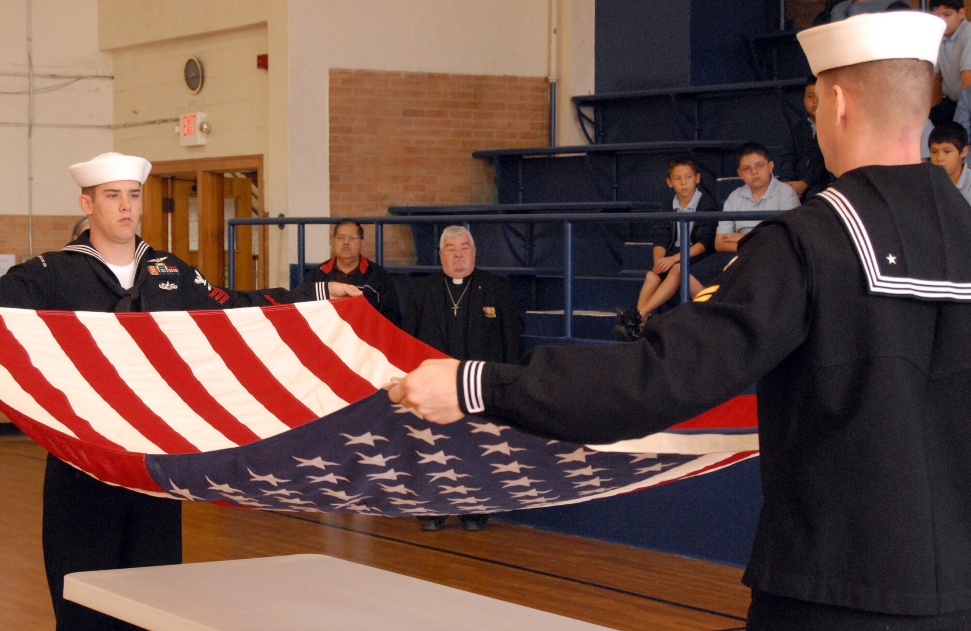 Petty Officer First Class David Norman and First Class Petty Officer Steven Vlasich both from the Center for Information Dominance Navy Detachment, Goodfellow Air Force Base, Texas, fold the U.S. flag and presented it to the Angelo Catholic School, San Angelo, Texas at a Veterans' Day Ceremony on Nov. 11.  The sailors conducted the flag ceremony and flew the flag for the school of approximately 80 students. (U.S. Air Force photo by Senior Master Sgt. Robert Martinez)