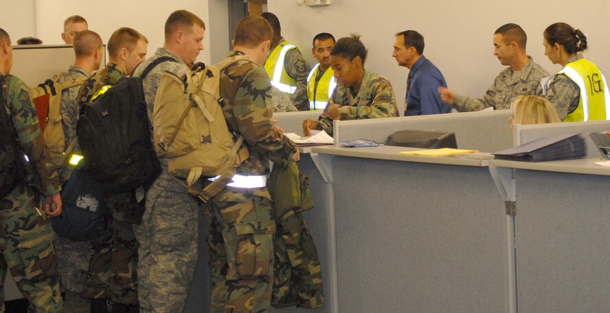 Members of the 341st Force Support Squadron work together to get personnel processed during a deployment line scenario in building 3080. Several members of the AFSPC IG take note of the operations Nov. 5. (U.S. Air Force photo/John Turner)
