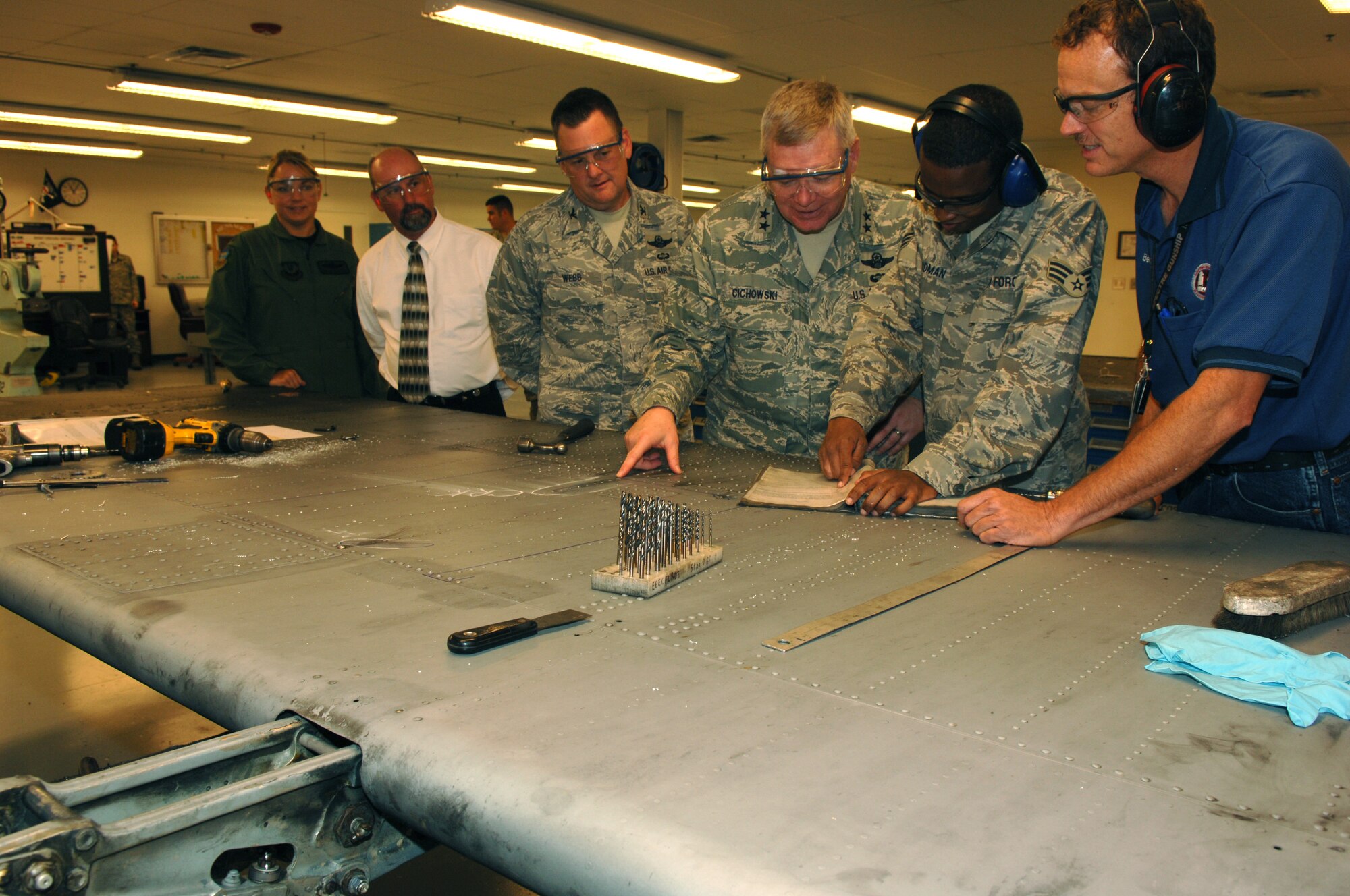 Senior Airman Bryce Goodman; 1st Special Operations Equipment Maintenance Squadron fabrication flight; and Benny Grey; 1 SOEMS fabrication flight; show Maj. Gen. Kurt Cichowski; Air Force Special Operations Command vice commander; Col. Brad Webb; 1st Special Operations Wing commander; Lt Col. Shelley Rodriguez; 1 SOW Safety Office and Joe Freese; 1 SOW Voluntary Protection Program manager; how to repair a cracked inboard flap on a C-130.