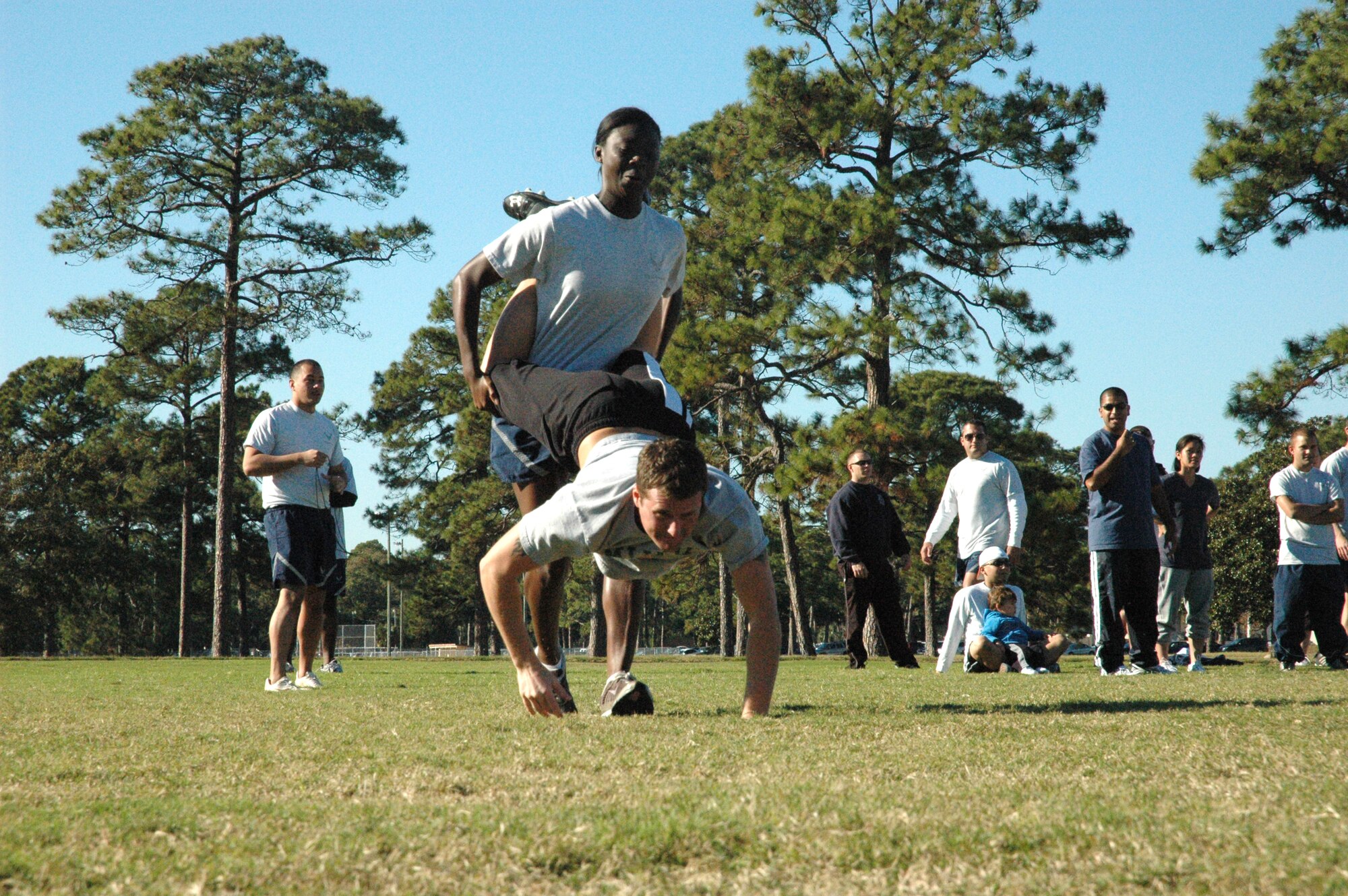 Participants watch while 2nd Lt. Vanessa Jessie, 325th Force Support Squadron Customer Service officer in charge and Senior Airmen Kristopher Legault, 325th Force Support Squadron Awards and Decorations Airman, “wheel barrel” to the football field’s 20-yard line during the Fastest Squadron competition. (U.S. Air Force photo by Staff Sgt. Vesta M. Anderson)
