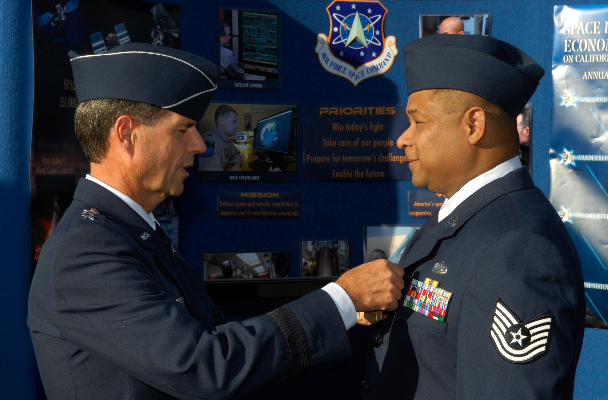 Lt. Gen. John T. Sheridan, SMC commander, presents Tech. Sgt Phillip Barton with the Air Force Commendation Medal at the Air Force Space Command display outside of the Los Angeles Coliseum before the start of the USC football game, Nov. 8. The ceremony was part of the events leading up to Air Force Week in Southern California. Air Force Week serves as the premier platform to share the Air Force story with our fellow citizens. The 2008 Air Force Weeks will include community visits and talks by Air Force officials, flight demonstrations and displays providing an up close and personal look at the men and women of the Air Force serving worldwide in defense of freedom. (Photo by Stephen Schester)