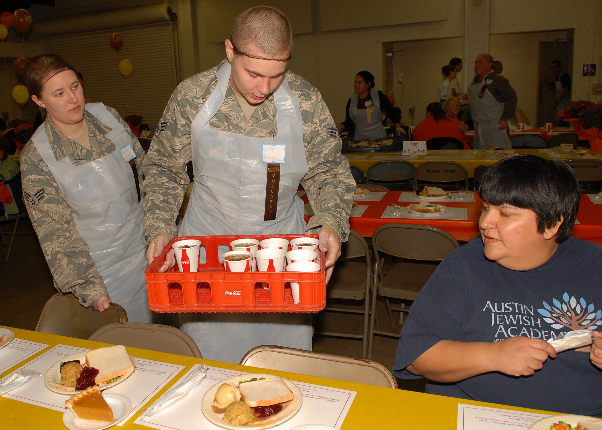 Senior Airman Sarah Whitehill (left), a volunteer from the 17th Training Support Squadron, and Senior Airman Scott Whitehill (center), a volunteer from the 17th Communications Squadron, hand out drinks to attendees at the annual H-E-B Feast of Sharing at the Wells Fargo Pavilion in San Angelo on Nov. 9.  (U.S. Air Force photo by Senior Airman Kasabyan Musal).