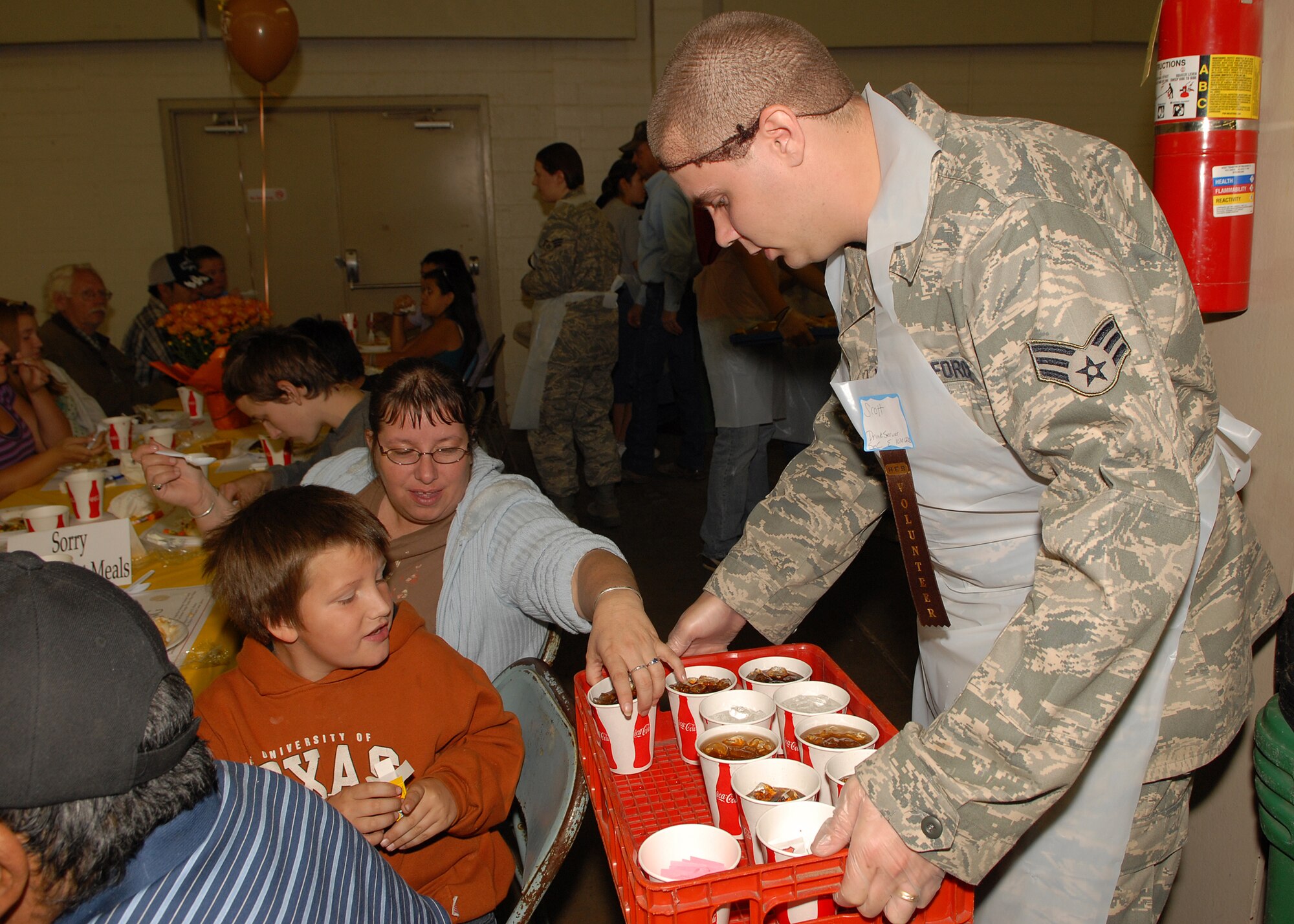 Senior Airman Scott Whitehill, a volunteer from the 17th Communications Squadron, hands out drinks to attendees at the annual H-E-B Feast of Sharing at the Wells Fargo Pavilion in San Angelo on Nov. 9.  (U.S. Air Force photo by Senior Airman Kasabyan Musal).