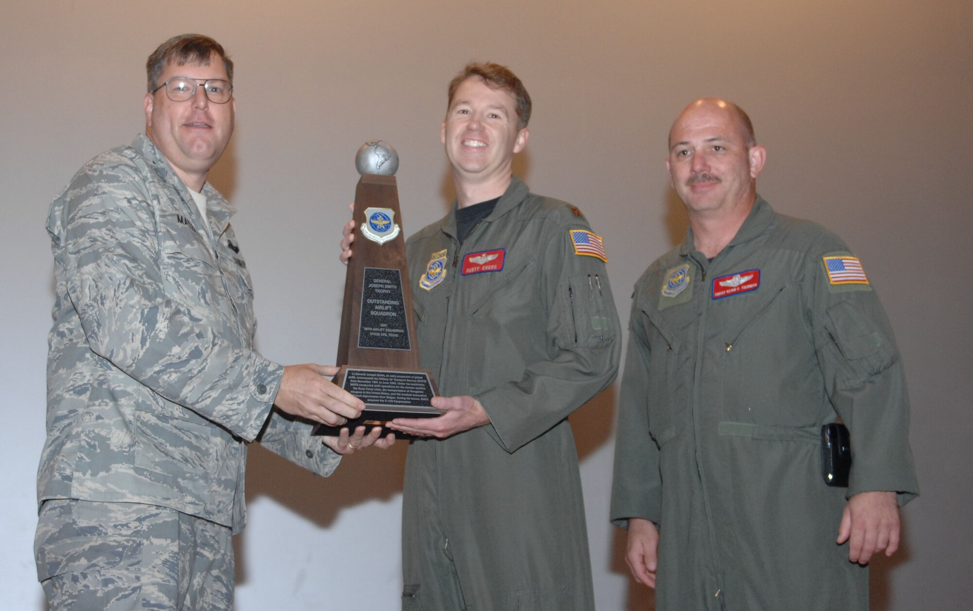 DYESS AIR FORCE BASE, Texas – Col. Bernard Mater, 317th Airlift Group commander, left, and Chief Master Sgt. Kevin Thurman, 39th Airlift Squadron superintendent, right, present Maj. Rusty Evers, 39th AS director of operations, center, with the General Joseph Smith Trophy in a ceremony here Nov. 4. The trophy acknowledged the 39th AS as the No. 1 Airlift Squadron in Air Mobility Command for 2007. The group’s other active flying unit, the 40th Airlift Squadron, won the award in 2004 and 2006. (U.S. Air Force photo/Senior Airman Domonique Simmons)
 
