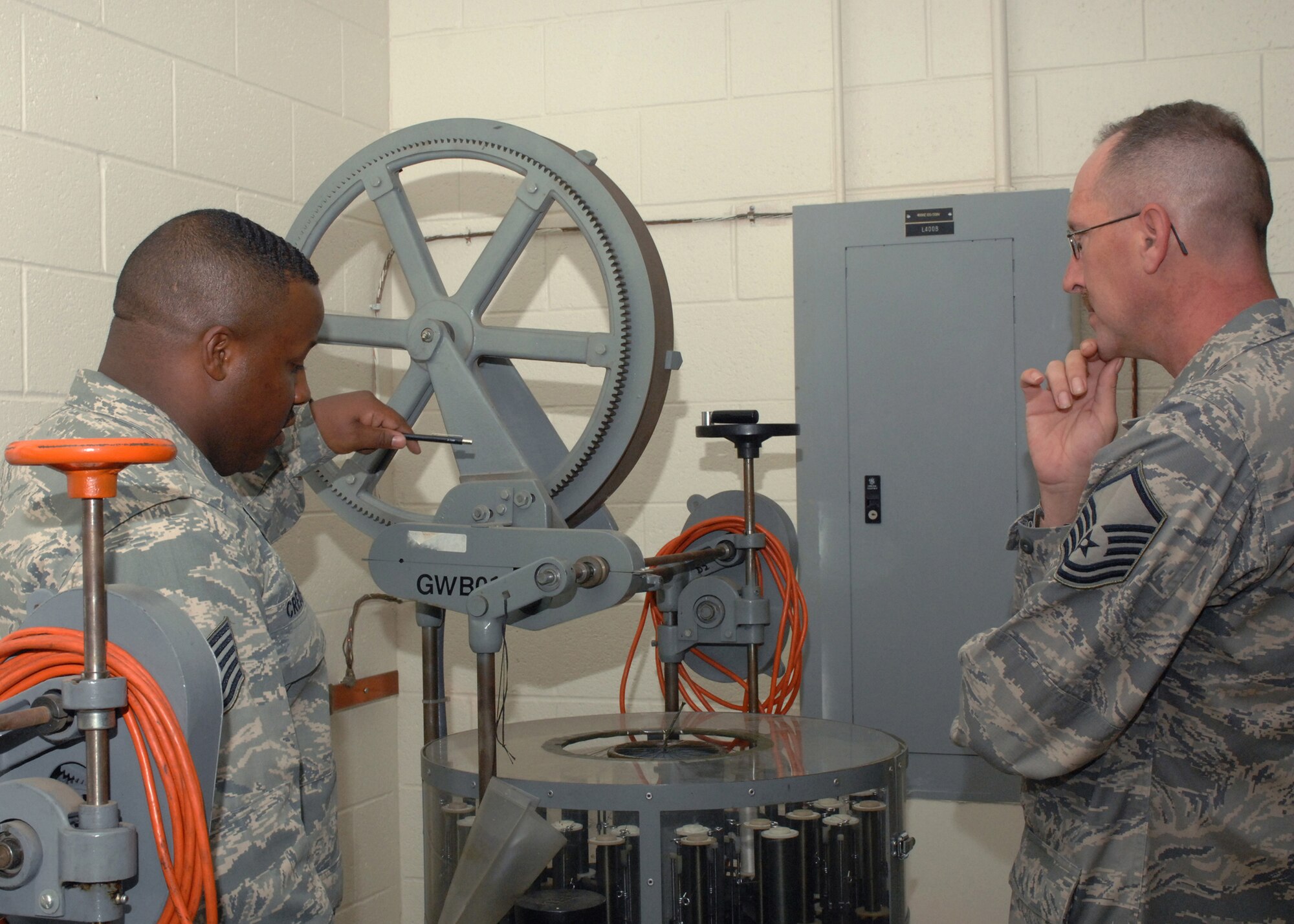 CANNON AIR FORCE BASE N.M. -- Tech. Sgt. Kent Creamer, 27th Special Operations Component Maintenance Squadron, shows Master Sgt. William Keely, 27th Special Operations Wing Safety Office, how the wire braiding machine operates. Volunteer Protection Program members, accompanied by Sergeant Keely, visited Cannon Nov. 3-7 to look at protection features on current equipment being used by the 27th SOCMS shop to cut down on injury and incident mishaps. (U.S. Air Force photo by Airman 1st Class James R. Bell)
