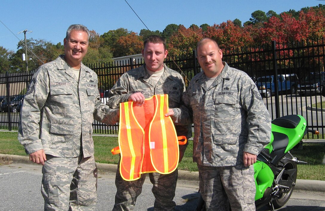 SEYMOUR JOHNSON AIR FORCE BASE, N.C. -- Airman First Class James Saunders (center), an aircraft hydraulics systems specialist receives one of 12 motorcycle safety vests from Master Sgt. Chris Scher (right), 916th Ground Safety NCO. Senior Master Sgt. Dave Theriot (left), fabrication flight chief also received a vest as part of the Fall Safety Campaign which helps put emphasis on preventing traffic fatalities. With gas pricing soaring this year, more military members are choosing to ride motorcycles, so the Air Force Reserve Command Safety Office is helping unit safety representatives by providing free safety vests. Reservists of the 916th can get their free vest from the 916th Safety Office while supplies last.