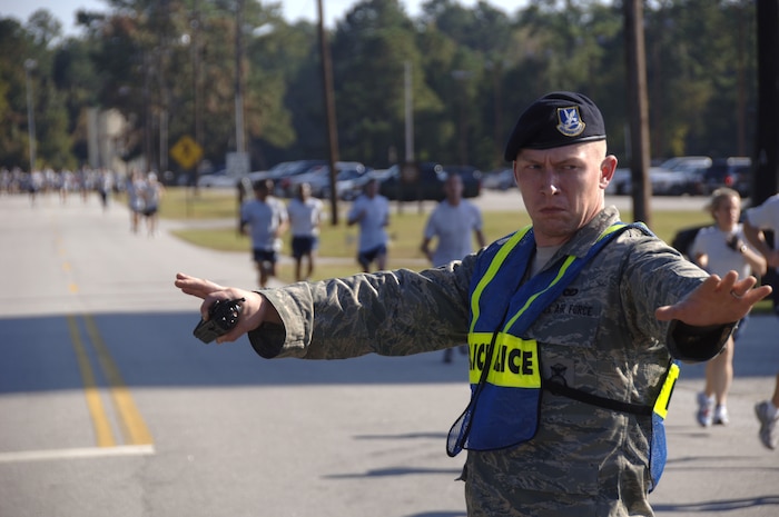 Airman Joshua Long stops traffic to allow Airmen to continue running down Davis Dr. on Charleston AFB Nov. 7. More than 400 Airmen from various squadrons came out to participate in the monthly challenge. Airman Long is assigned to the 437th Security Forces Squadron. (U.S. Air Force photo/Senior Airman Timothy Taylor)