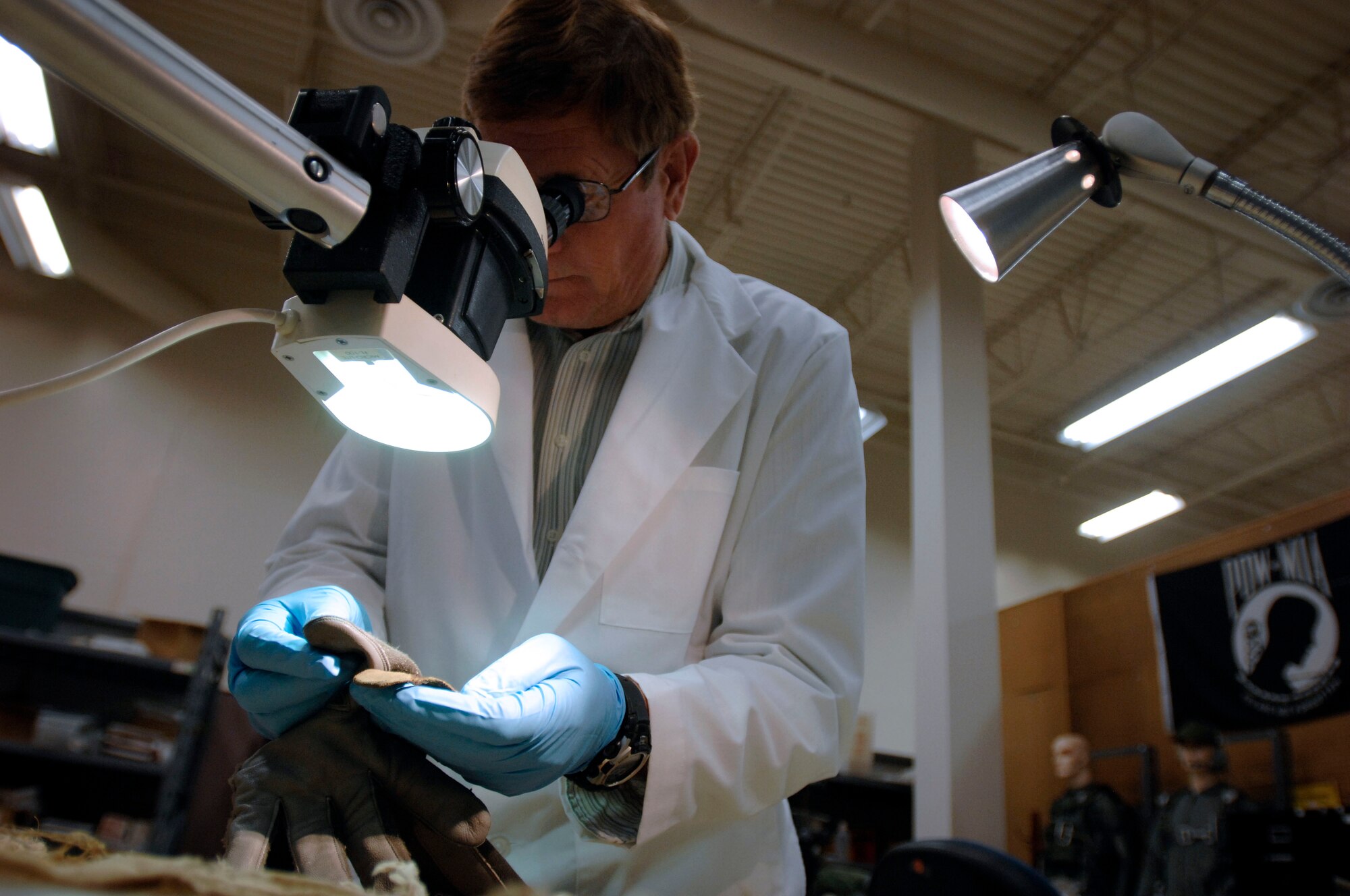 Equipment analyst Neill Smith inspects a glove sample recovered from an aircraft crash site in an attempt to identify the servicemember lost in the crash. The analysts at the Life Sciences Equipment Laboratory at Brooks City-Base in San Antonio use equipment at the lab as comparisons to the artifacts shipped to the lab from a recovery site. DoD photo by Fred W. Baker III 