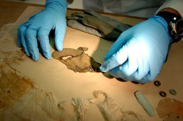 An equipment analyst at the Life Sciences Equipment Laboratory inspects fabric recovered from a site in an attempt to identify the servicemember lost in the crash. The lab, at Brooks City-Base in San Antonio, helps the Joint POW/MIA Accounting Command identify servicemembers where recovery sites yield little or no human remains. DoD photo by Fred W. Baker III  
