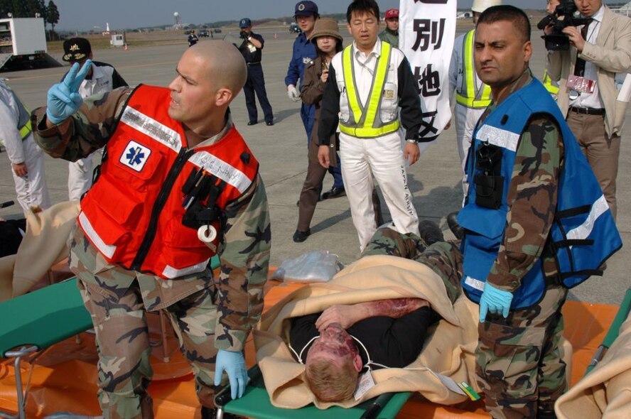 MISAWA AIR BASE, Japan -- Petty Officer 2nd Class Orlando Garcia, Naval Air Facility Misawa, calls for two more stretcher bearers, as he and Capt. Zahid Siddique, 35th Medical Group, prepare to move a victim to a treatment tent, during an aircraft mishap exercise held at nearby Misawa Airport, Nov. 6, 2008. Petty Officer 2nd Class Garcia and Captain Siddique are both part of the Misawa military community's Primary Response Team. (U.S. Navy photo by Chief Petty Officer Brian Naranjo)