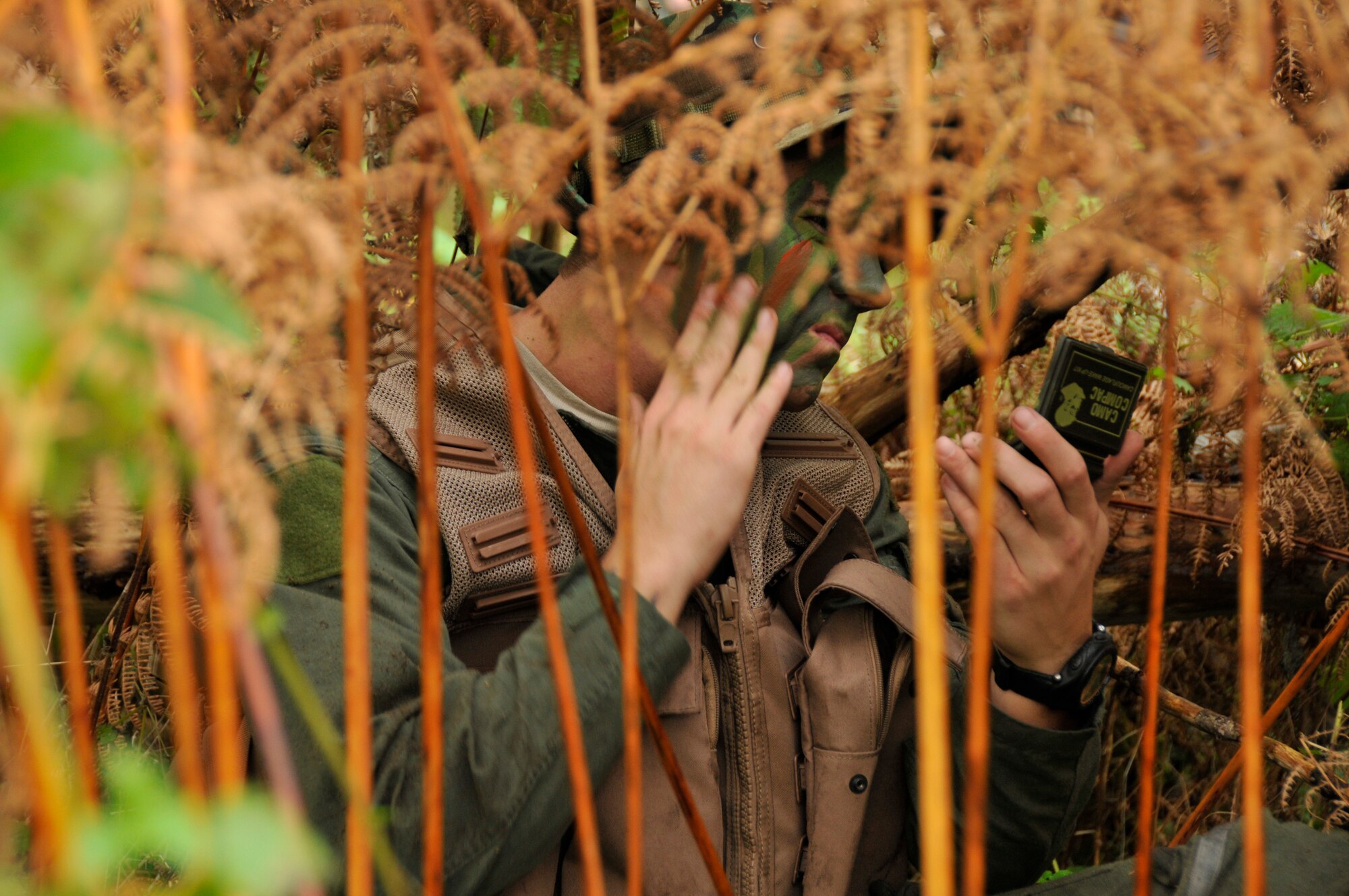 Staff Sgt. Sean Marlow, 48th Operational Support Squadron wing SERE specialist, applies camouflage paint to his face and clothes to conceal his location Nov. 11 at Stanford Training Area in Thetford, England. Survival, evasion, resistance and escape (SERE) instructors performed a refresher course for future deployers. (U.S. Air Force photo by Airman 1st Class Perry Aston)