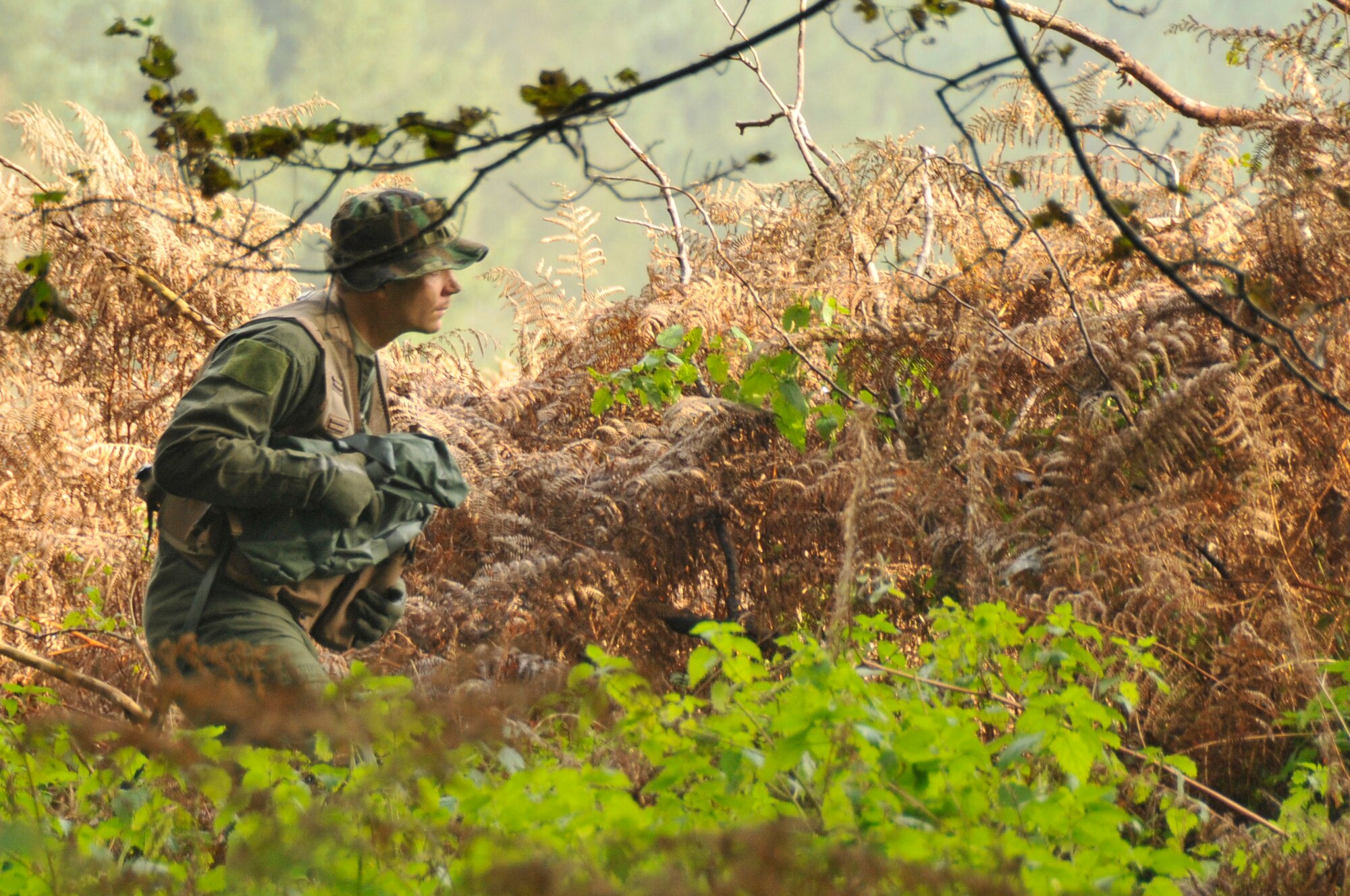Staff Sgt. Sean Marlow, 48th Operational Support Squadron wing SERE specialist, moves through the woods to find a suitable hiding place Nov. 11 at Stanford Training Area in Thetford, England. Survival, evasion, resistance and escape (SERE) instructors performed a refresher course for future deployers. (U.S. Air Force photo by Airman 1st Class Perry Aston)