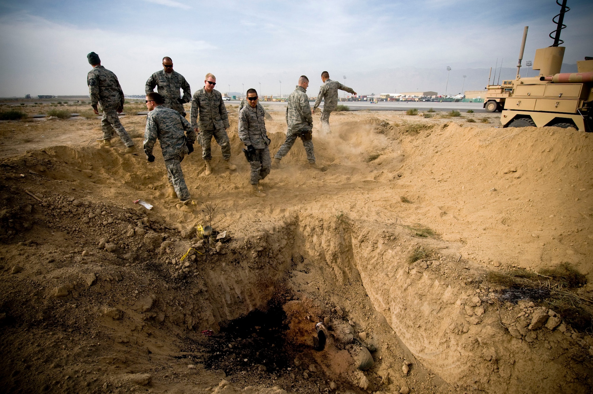 The 755th Air Expeditionary Group Explosive Ordinance Disposal team inspects a job well-done after a controlled burn on the flightline at Bagram Air Field, Afghanistan, Nov. 7. The dirt berm built-up around the site helped to provide a barrier in the event of a full-scale or premature detonation. (U.S. Air Force photo by Staff Sgt. Samuel Morse/Released)