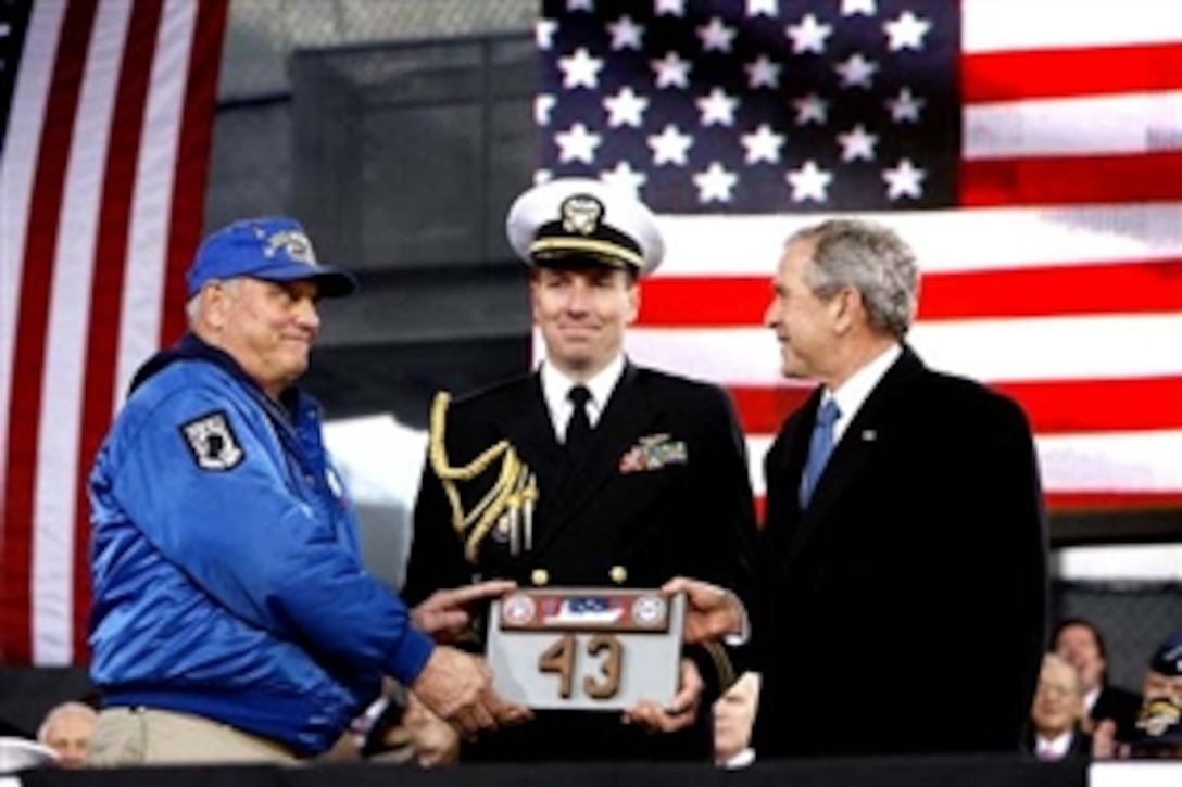 President George W. Bush is presented a piece of the flight deck of the USS Intrepid by Mike Hallahan, left, president of the United War Veterans Council of New York, also joined by military aide U.S. Navy Lt.Cmdr. Clay Beers, during the rededication ceremony Tuesday, Nov. 11, 2008, for the Intrepid Sea, Air and Space Museum in New York. 